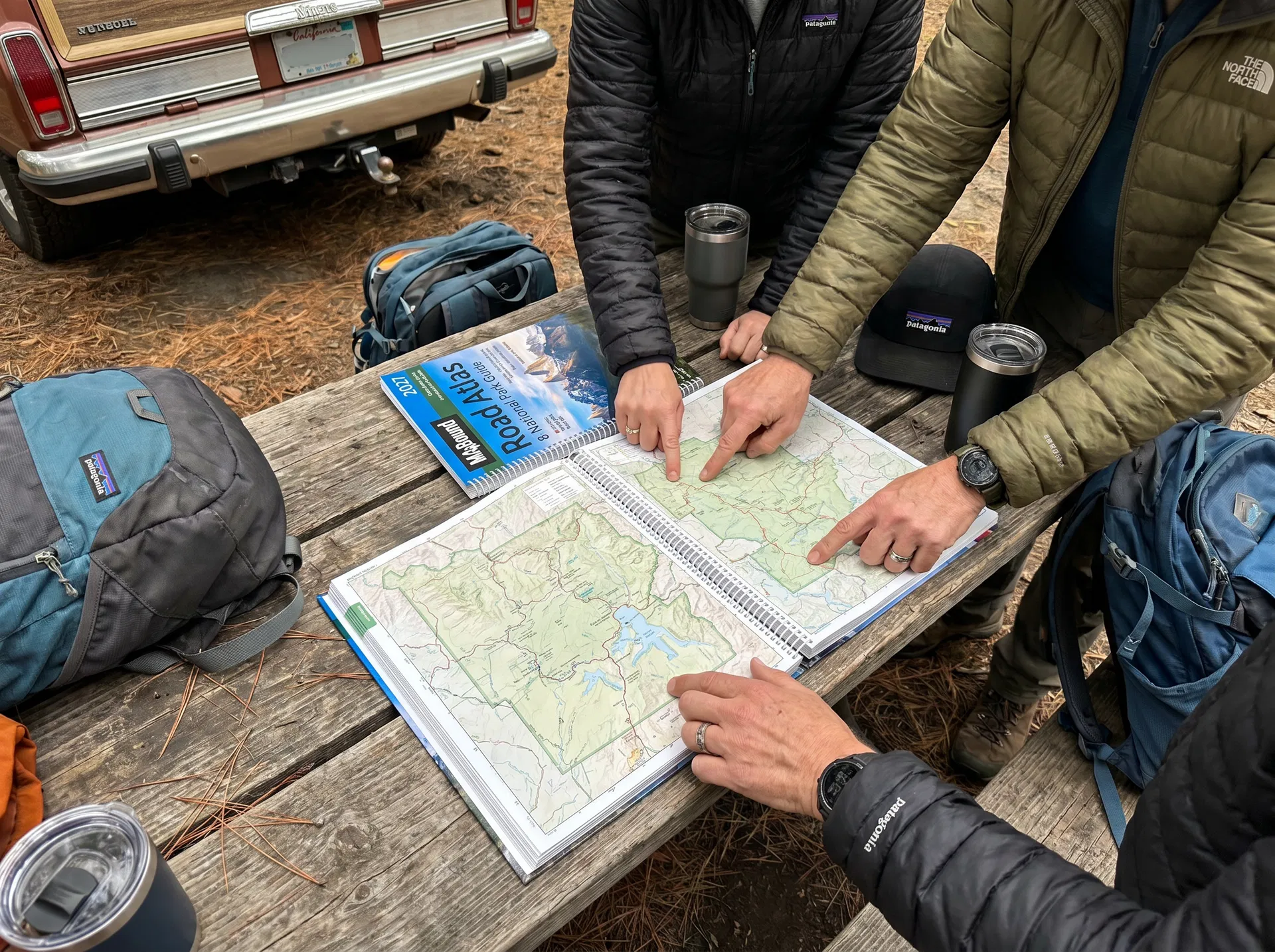 Travel companions gathered around the MapBound atlas at a roadside stop