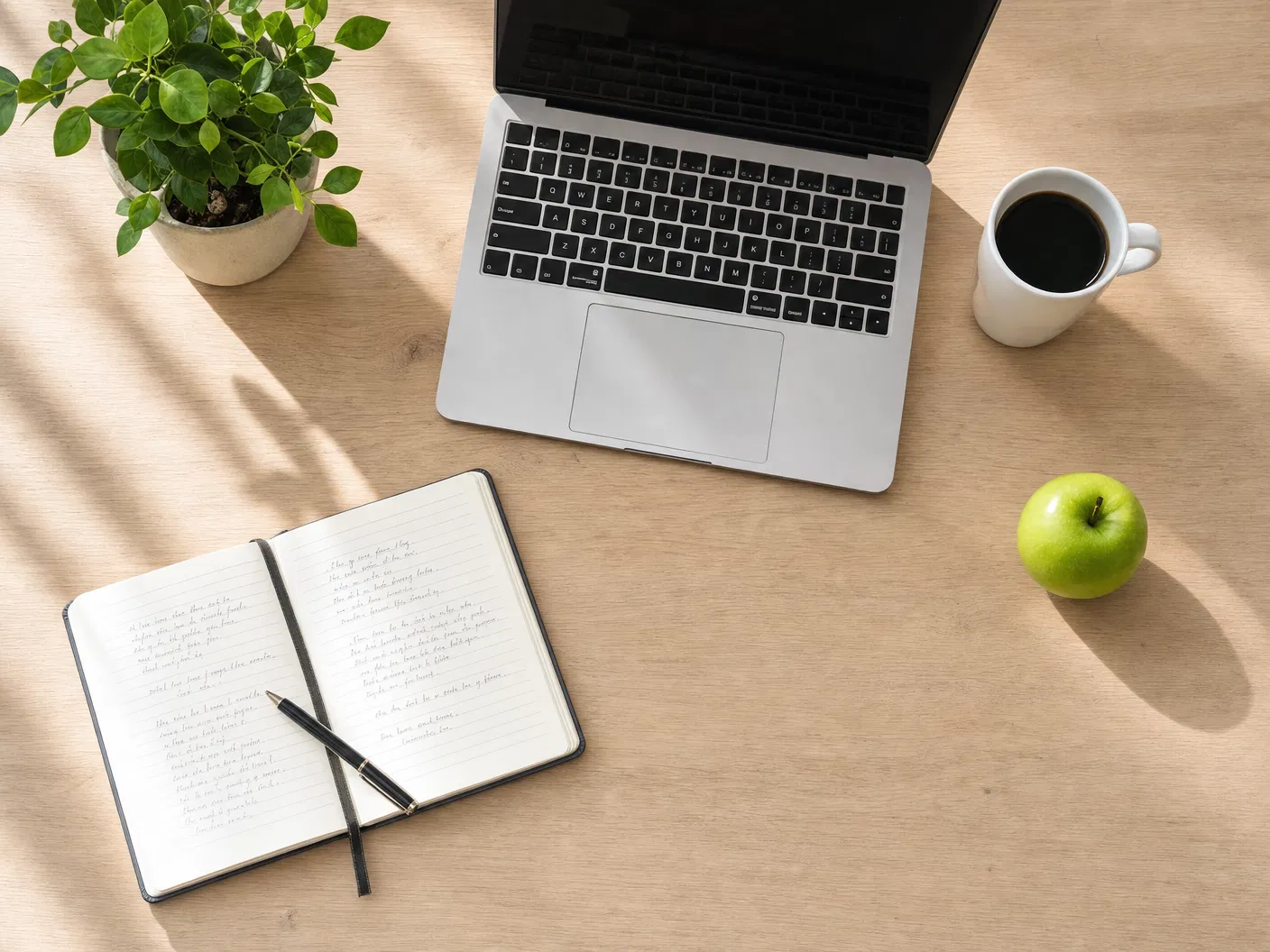 Strategy session flat lay with notebook, laptop, and a green apple.