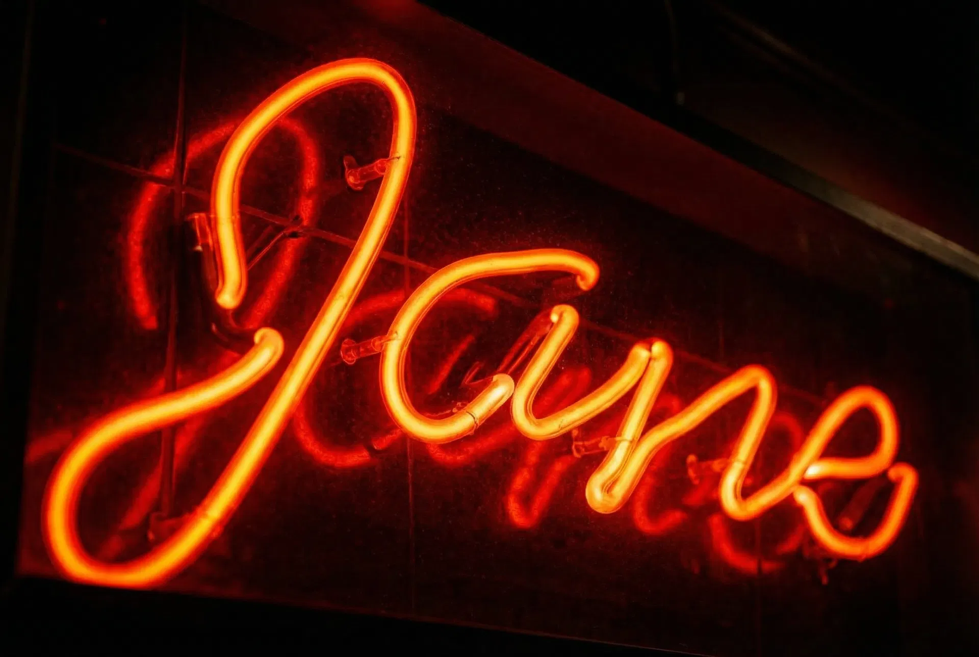 Close-up of Jane's red neon sign glowing in the dark, showing the elegant cursive lettering