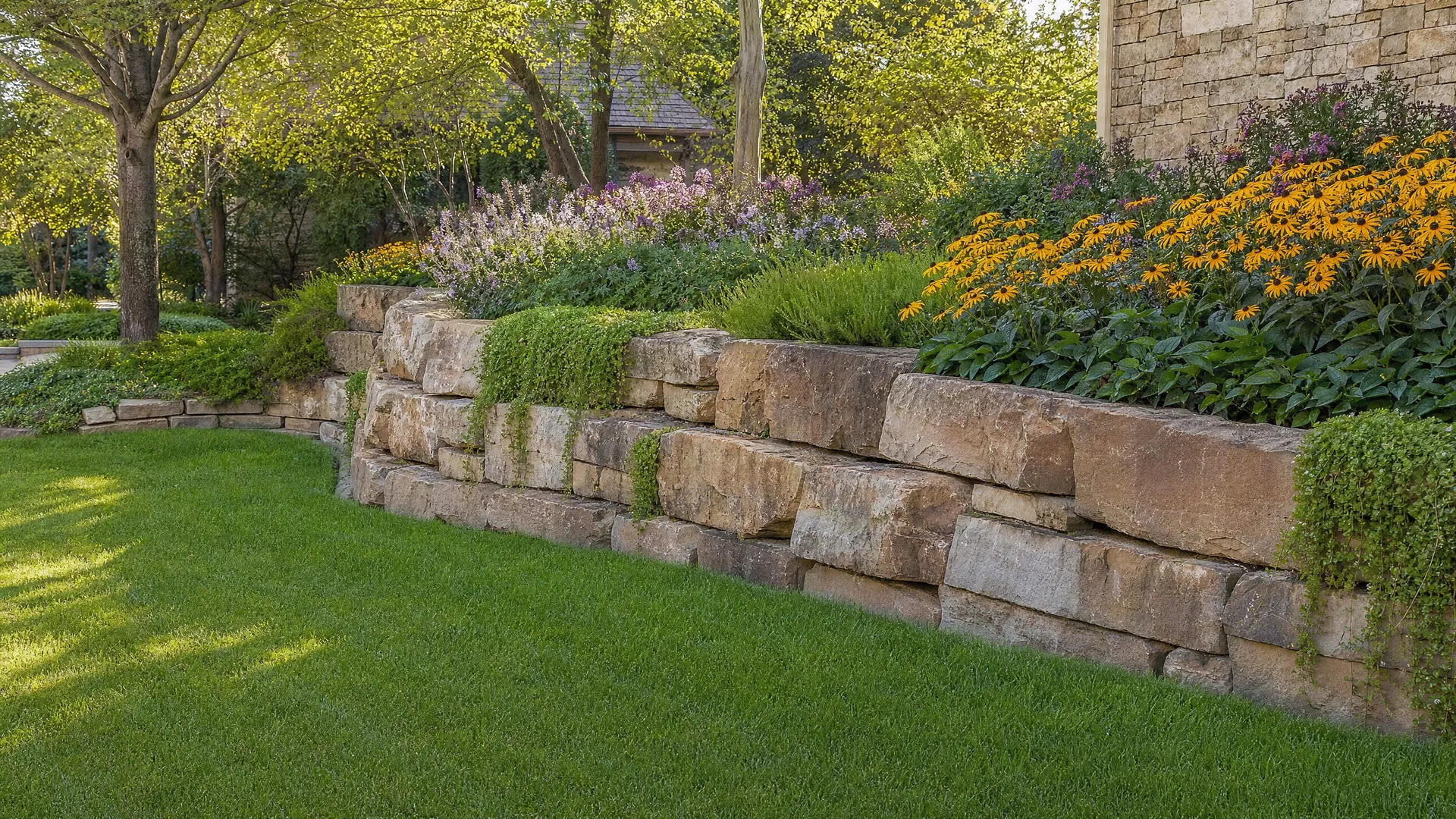 Natural stone retaining wall with garden beds by Zedo Construction