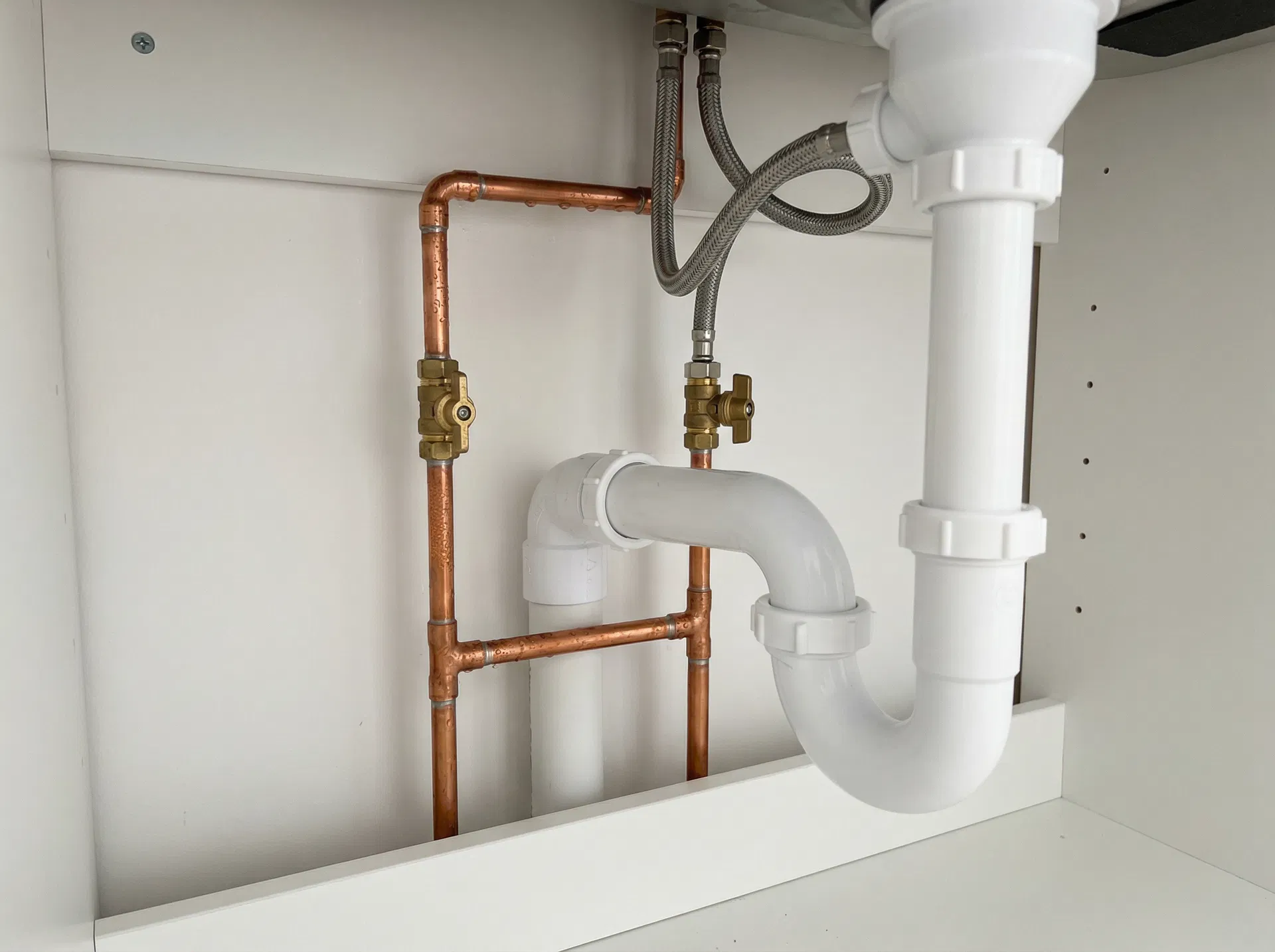 Plumbing pipes under a sink — plumbing services in Chorley