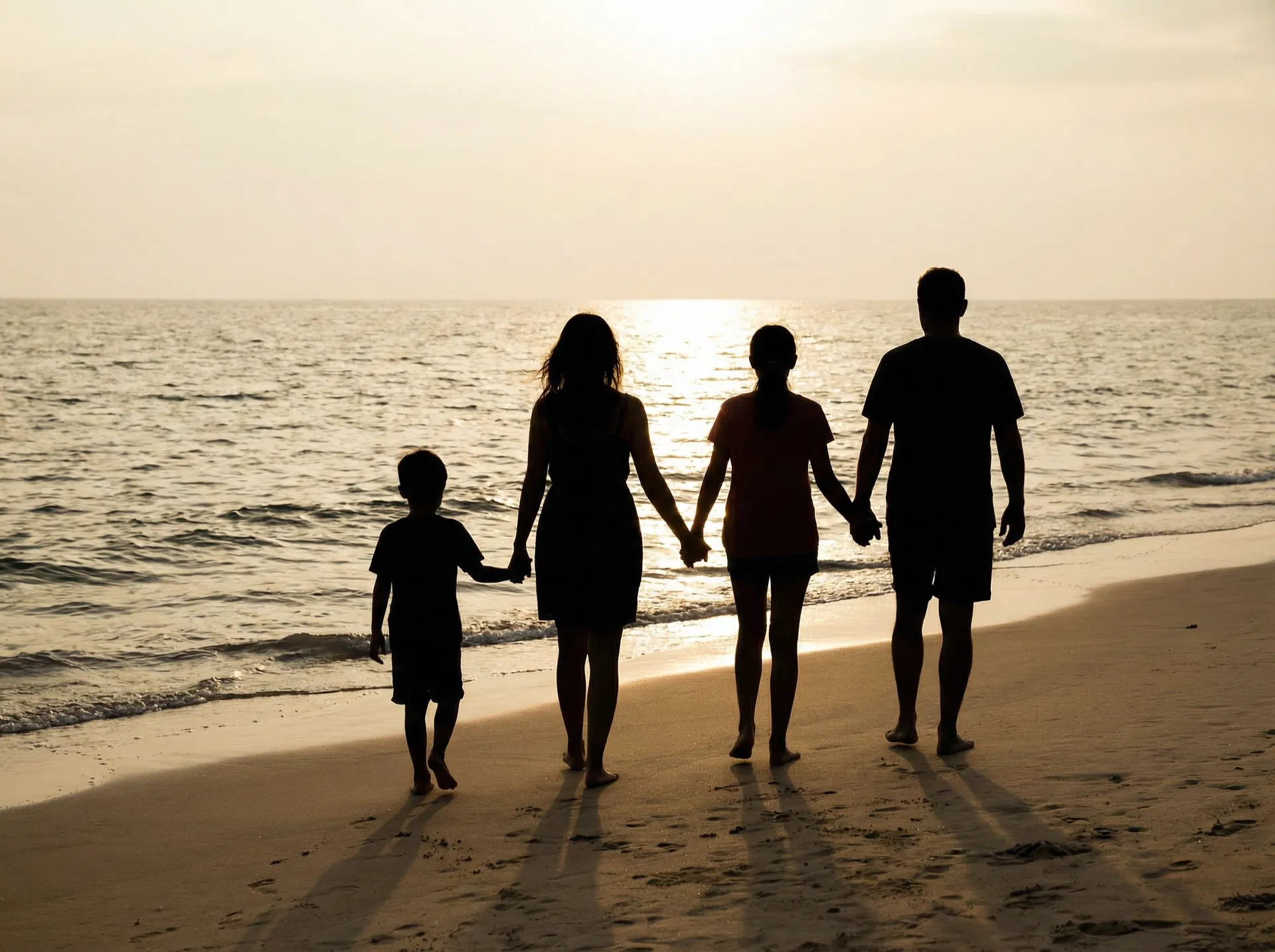 Family walking together on the beach at golden hour