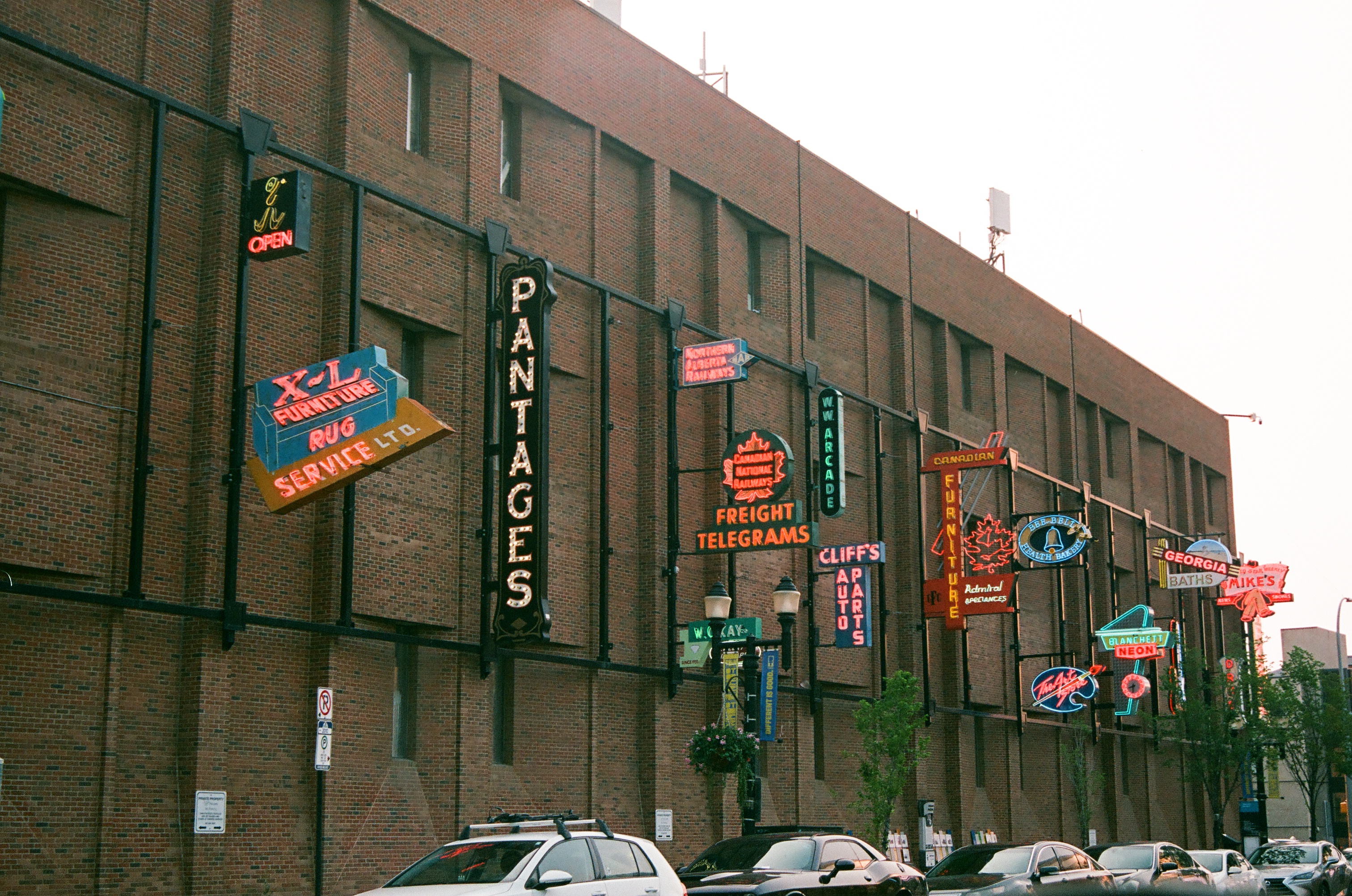 analog film photograph of a brick building facade lined with vintage neon signs including Pantages, Freight Telegrams, and Cliff's Auto Parts