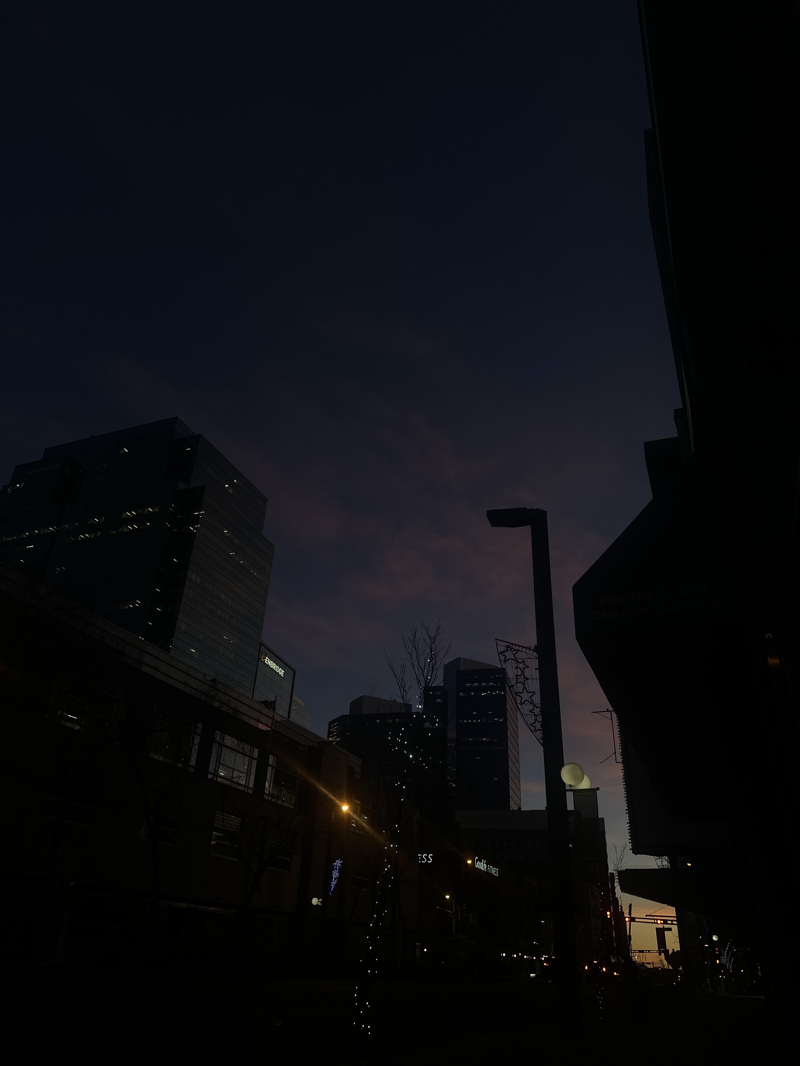 analog film photograph of a city street at dusk, buildings and streetlights reflected in deep blue twilight