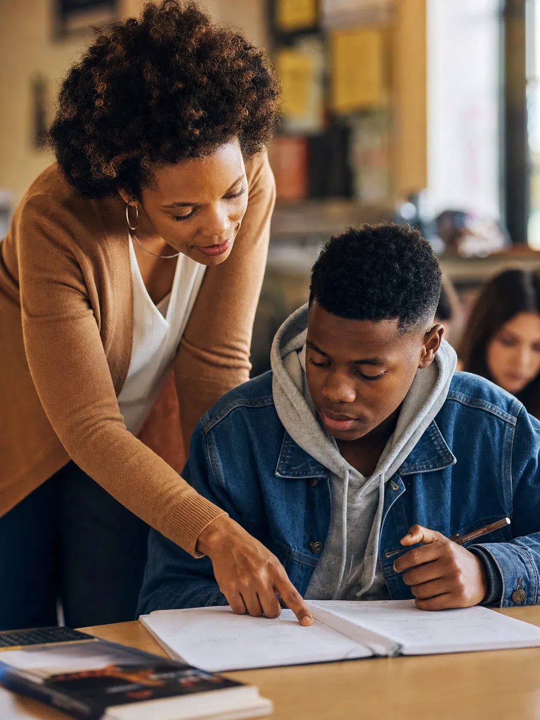 Teacher leaning over desk helping a teenage student with their work