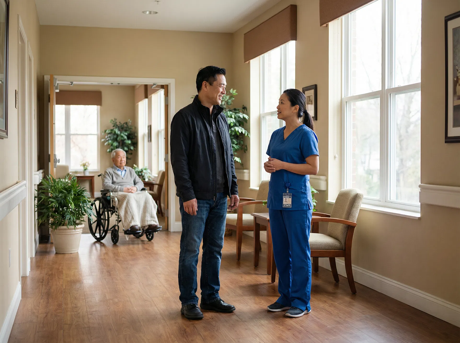 Adult son speaking with assisted living staff member in facility hallway