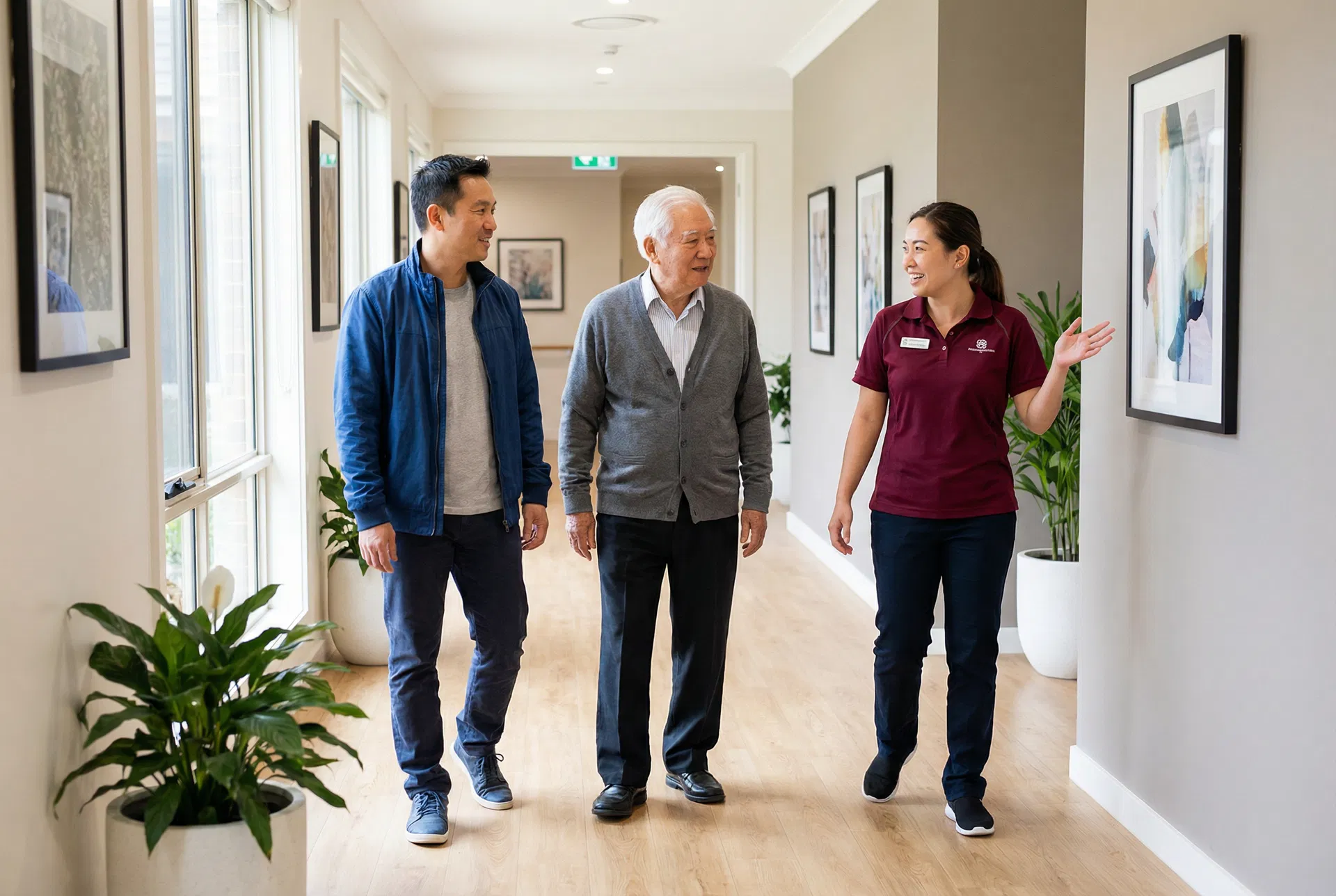 Asian son and elderly father touring assisted living facility with staff member