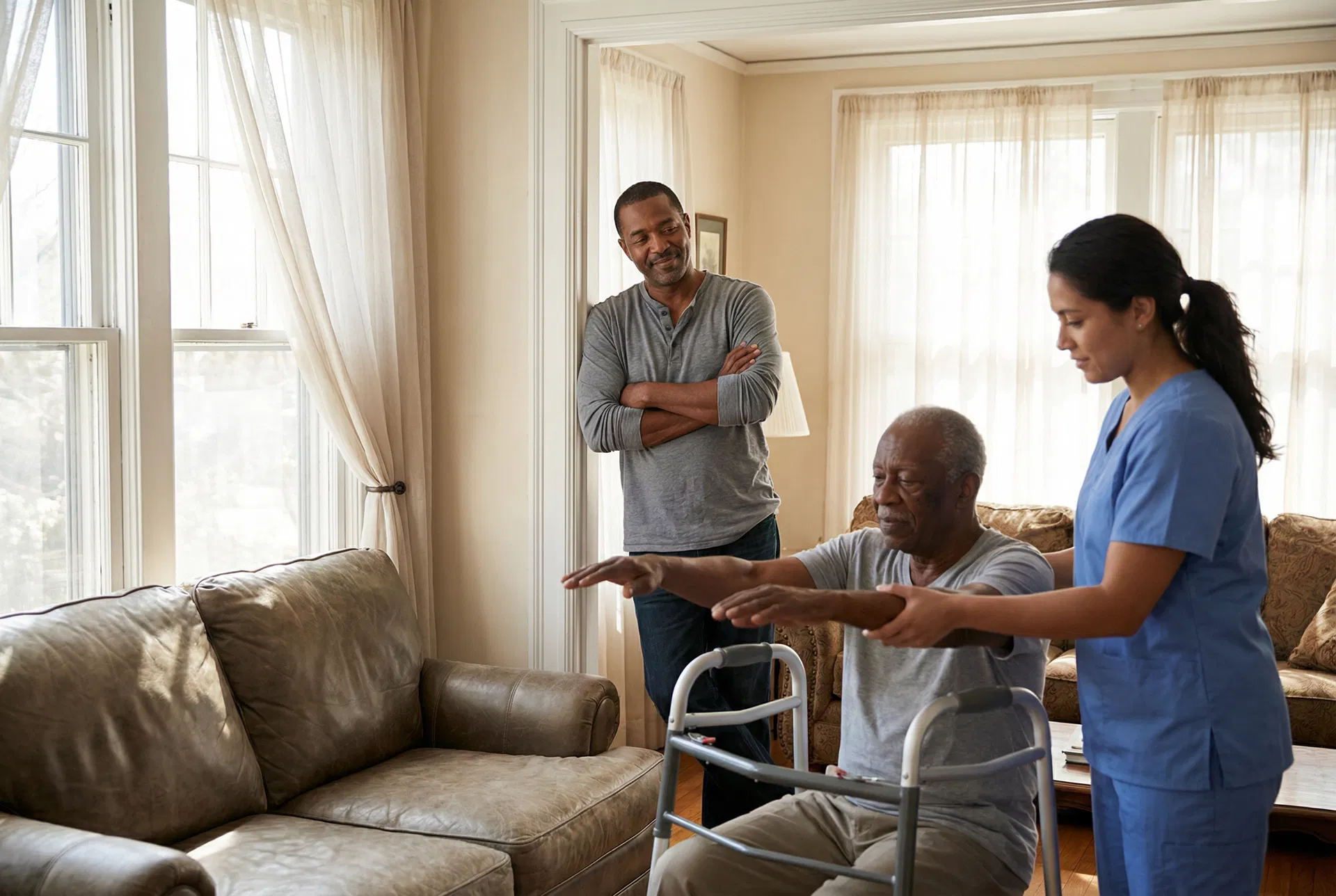 Black son watching home care aide help elderly father with physical therapy