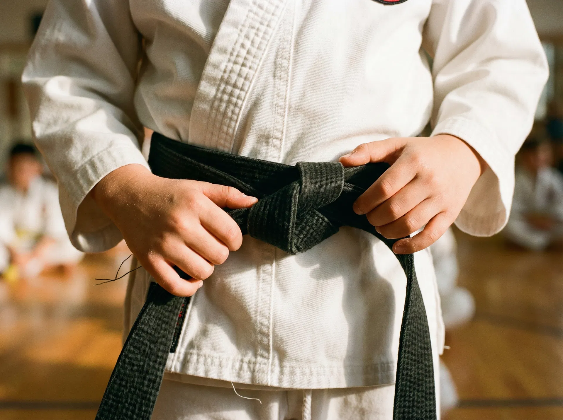 Kind bindet seinen Karate-Gürtel – Schritt für Schritt wachsen
