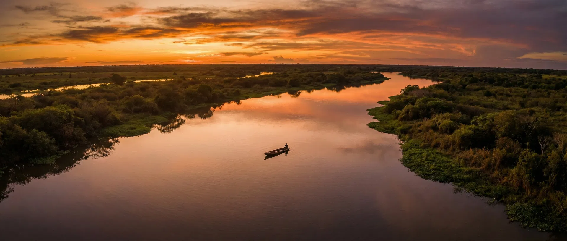 Pôr do sol no Pantanal com pescador no rio