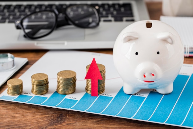 Piggy bank and growth chart with coins and laptop