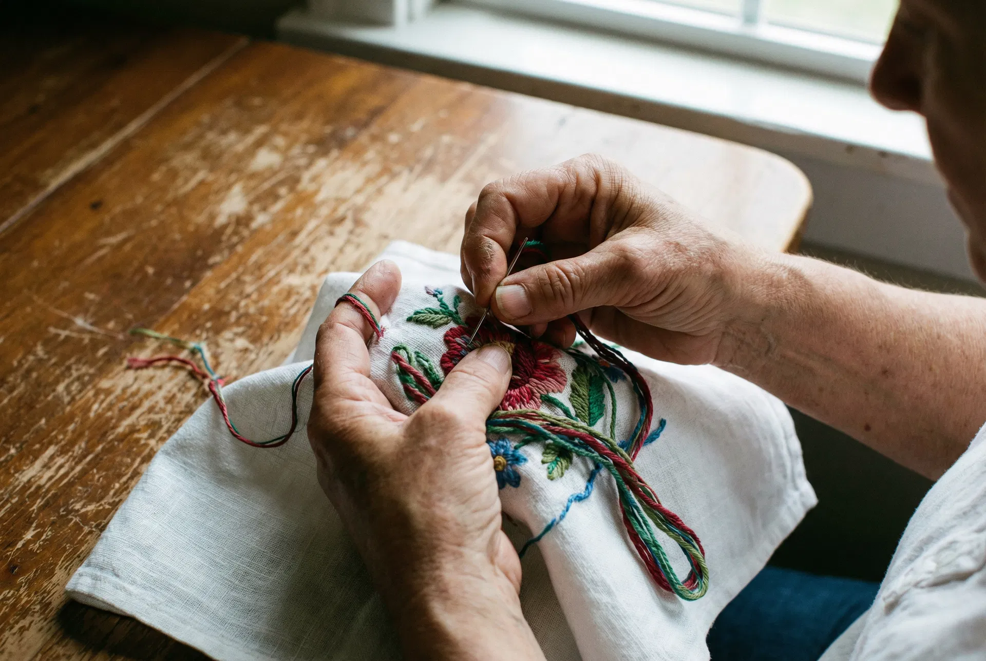 Mãos bordando pano de prato