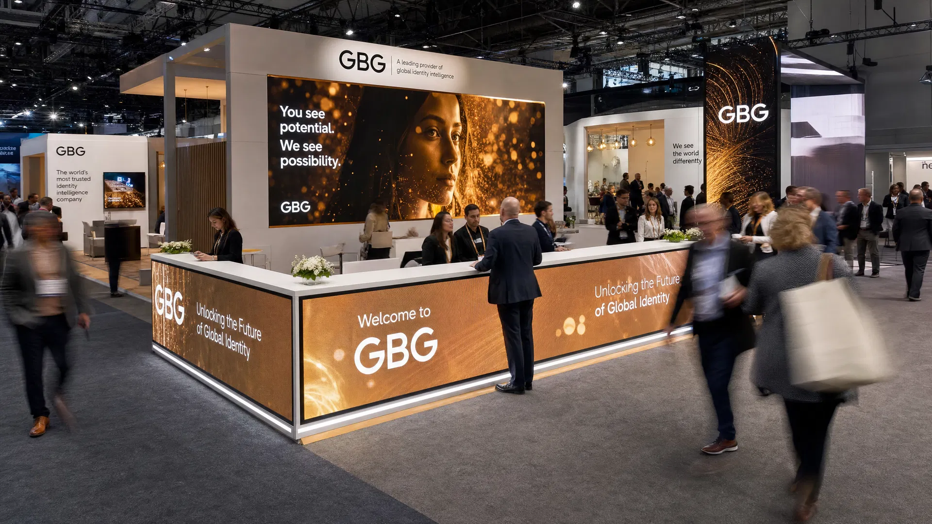 Wide shot of a busy trade show booth featuring multiple LED counters with visitors engaging with booth staff