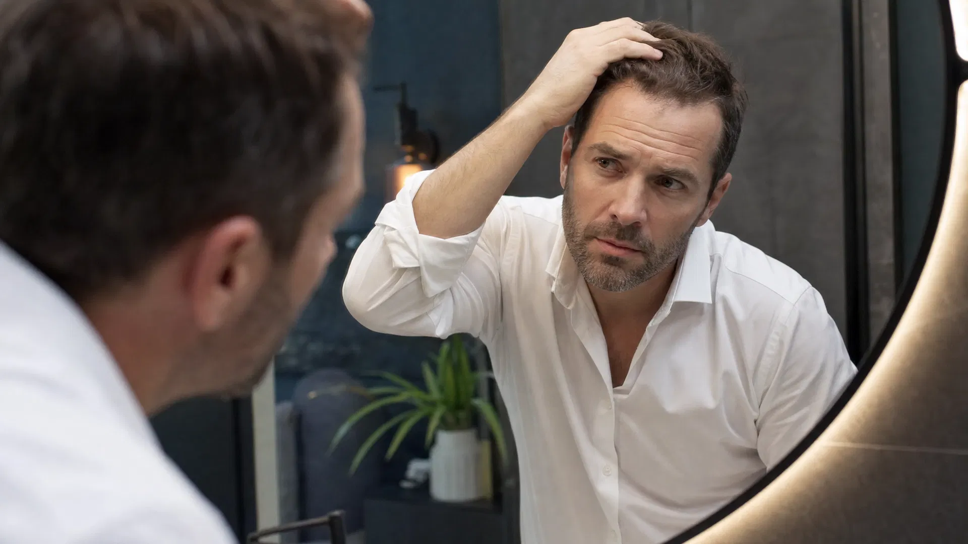 Man examining his hairline in the mirror, considering a hair transplant consultation