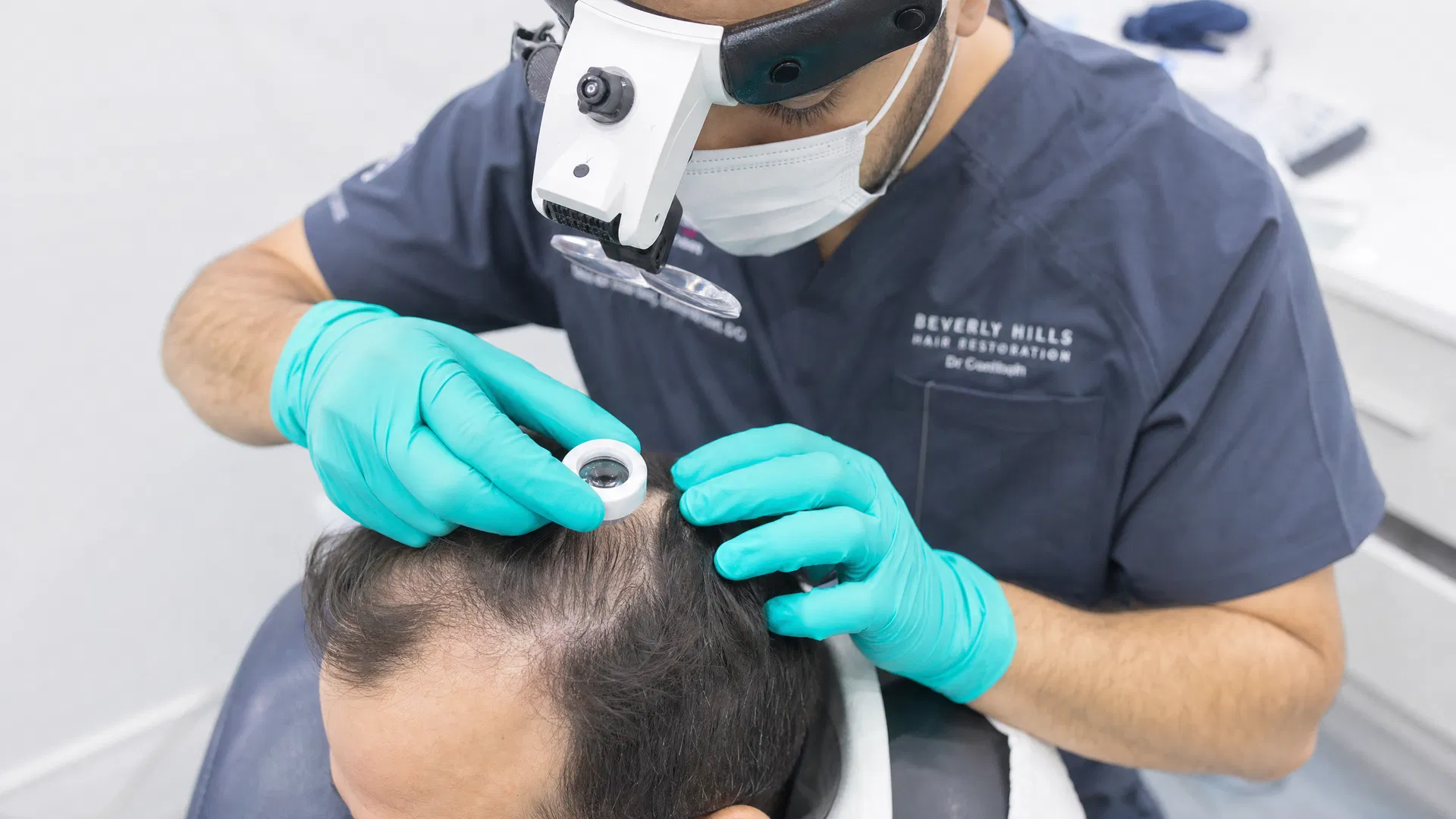 Hair transplant surgeon examining a patient's scalp and hairline before a procedure