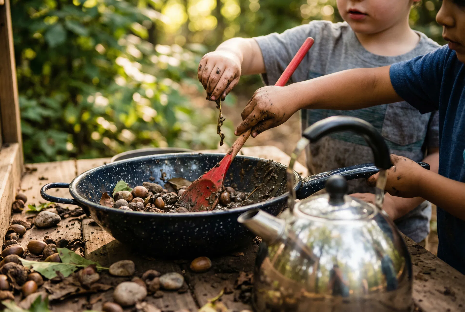 Children playing at an outdoor mud kitchen, stirring acorns and natural materials in an enamel pan