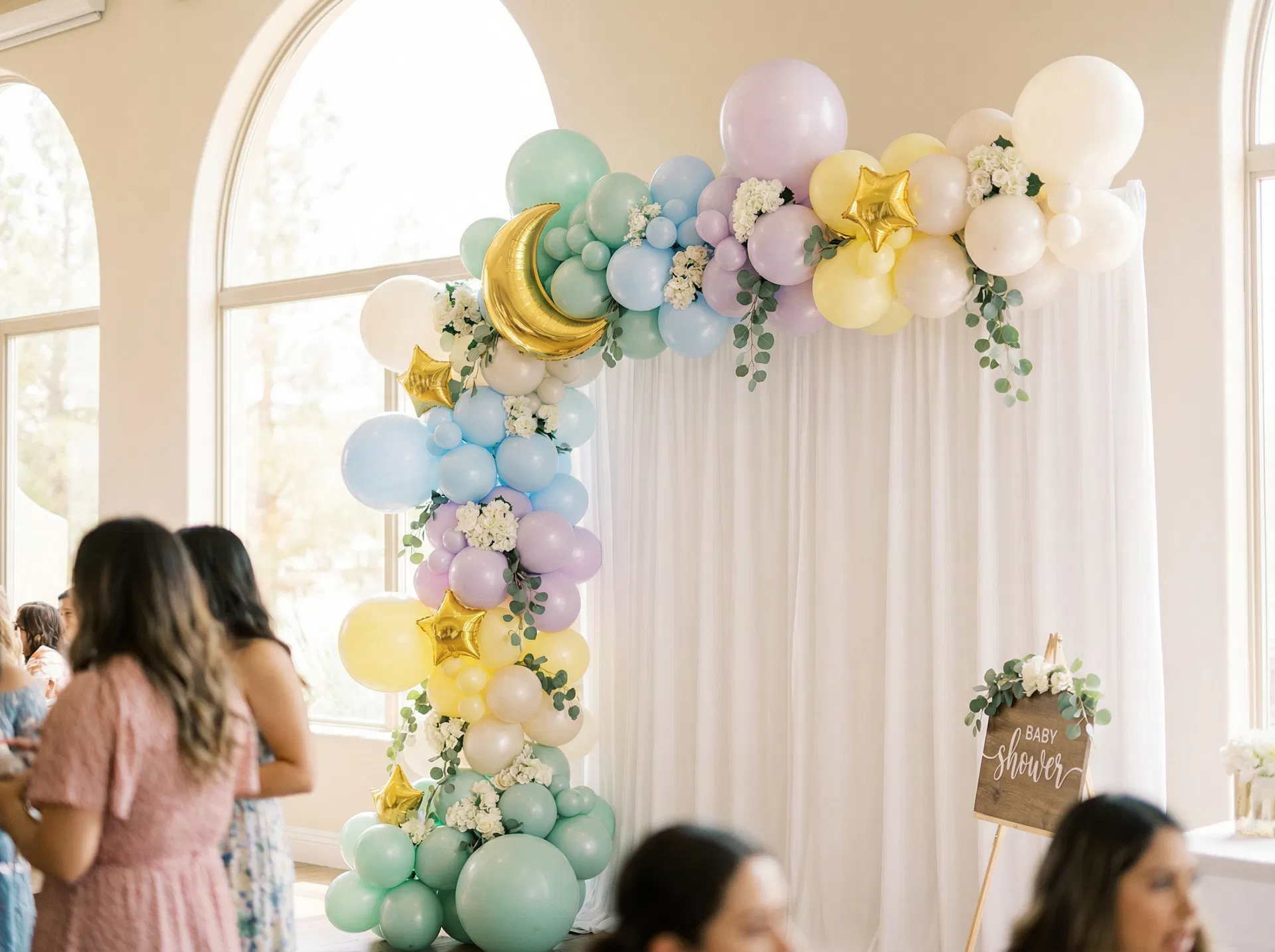 Elegant pastel organic half-arch balloon garland in mint green, baby blue, lavender, and soft yellow with gold moon and star foil balloons at a baby shower in El Paso, TX — Sweet & Sassy Creations