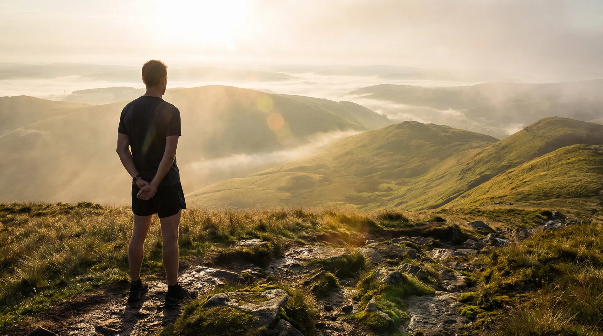 Man overlooking misty hills at golden hour
