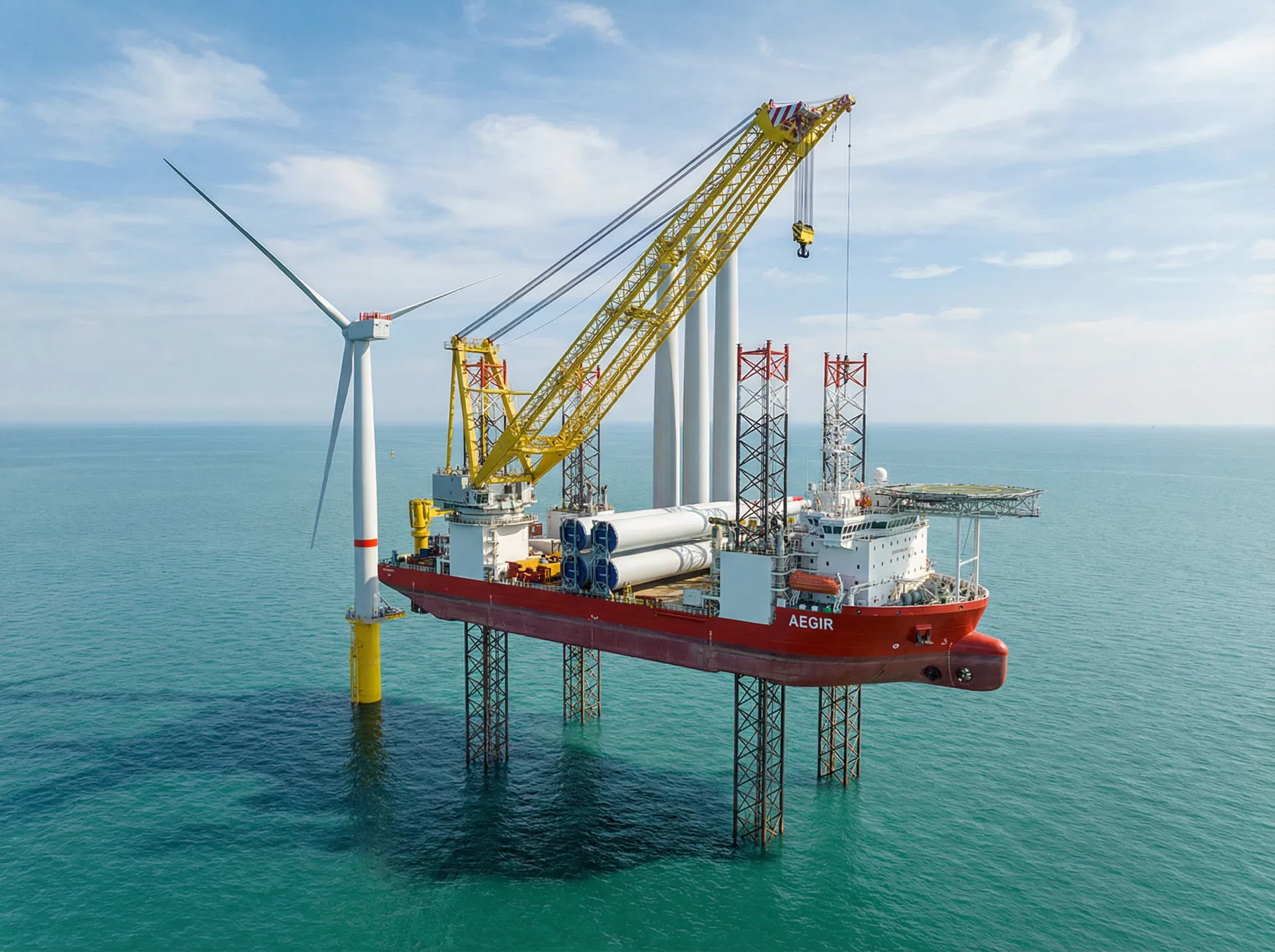 Jack-up installation vessel with legs extended, positioned next to offshore wind turbine