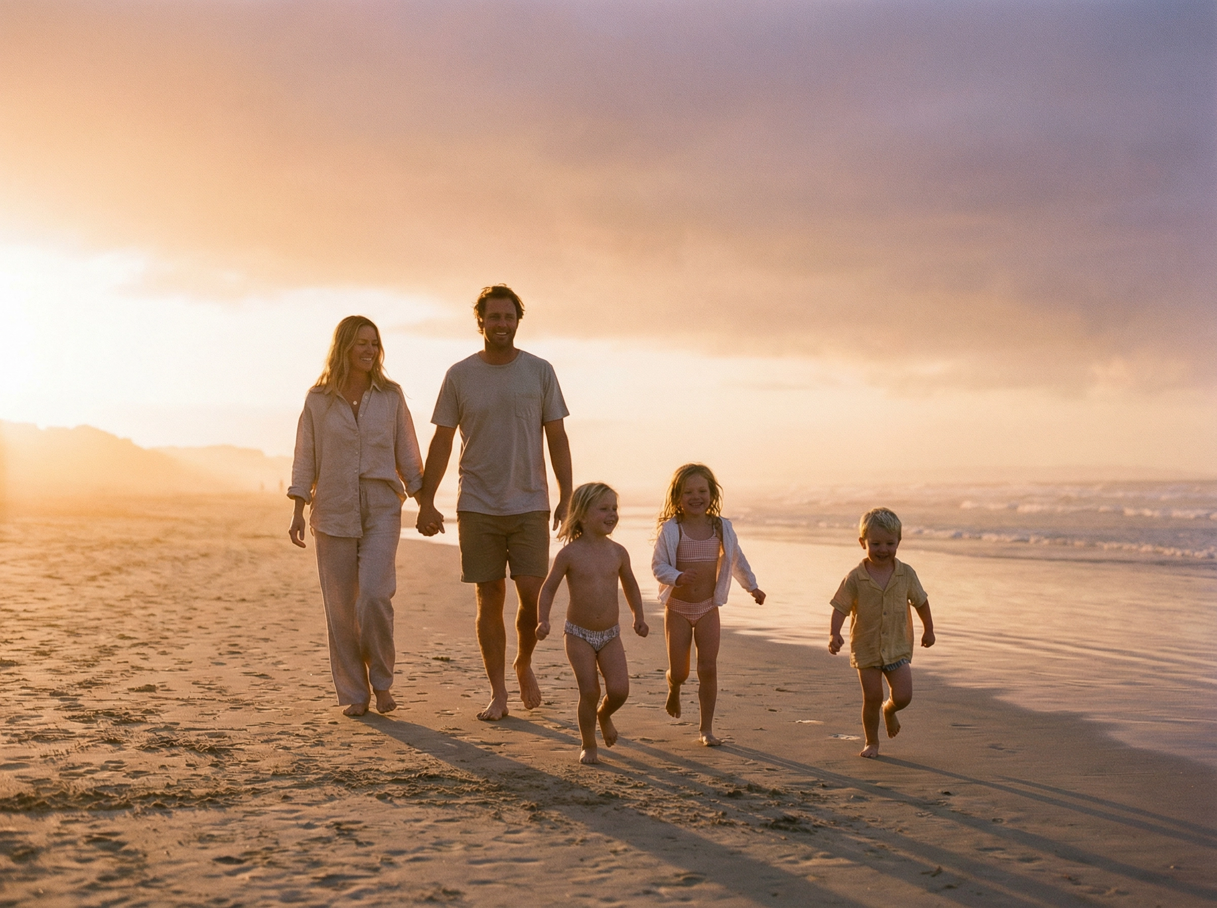 Family walking on beach at sunset