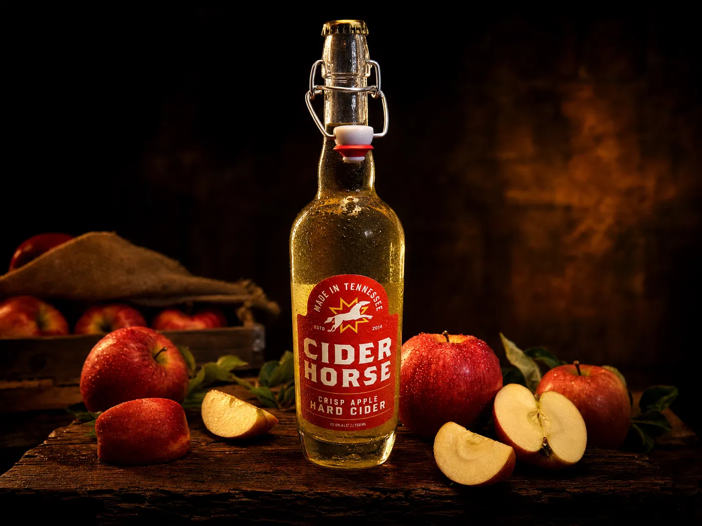 Cider Horse Crisp Apple Hard Cider swing-top bottle with red label surrounded by fresh red apples on a dark rustic wood surface