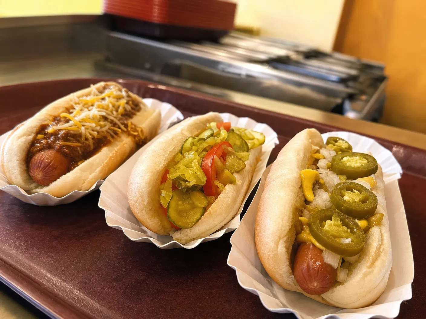 Three Franken Dogs hotdogs with chili, cheese, pickles, peppers, jalapeños, onions, and mustard