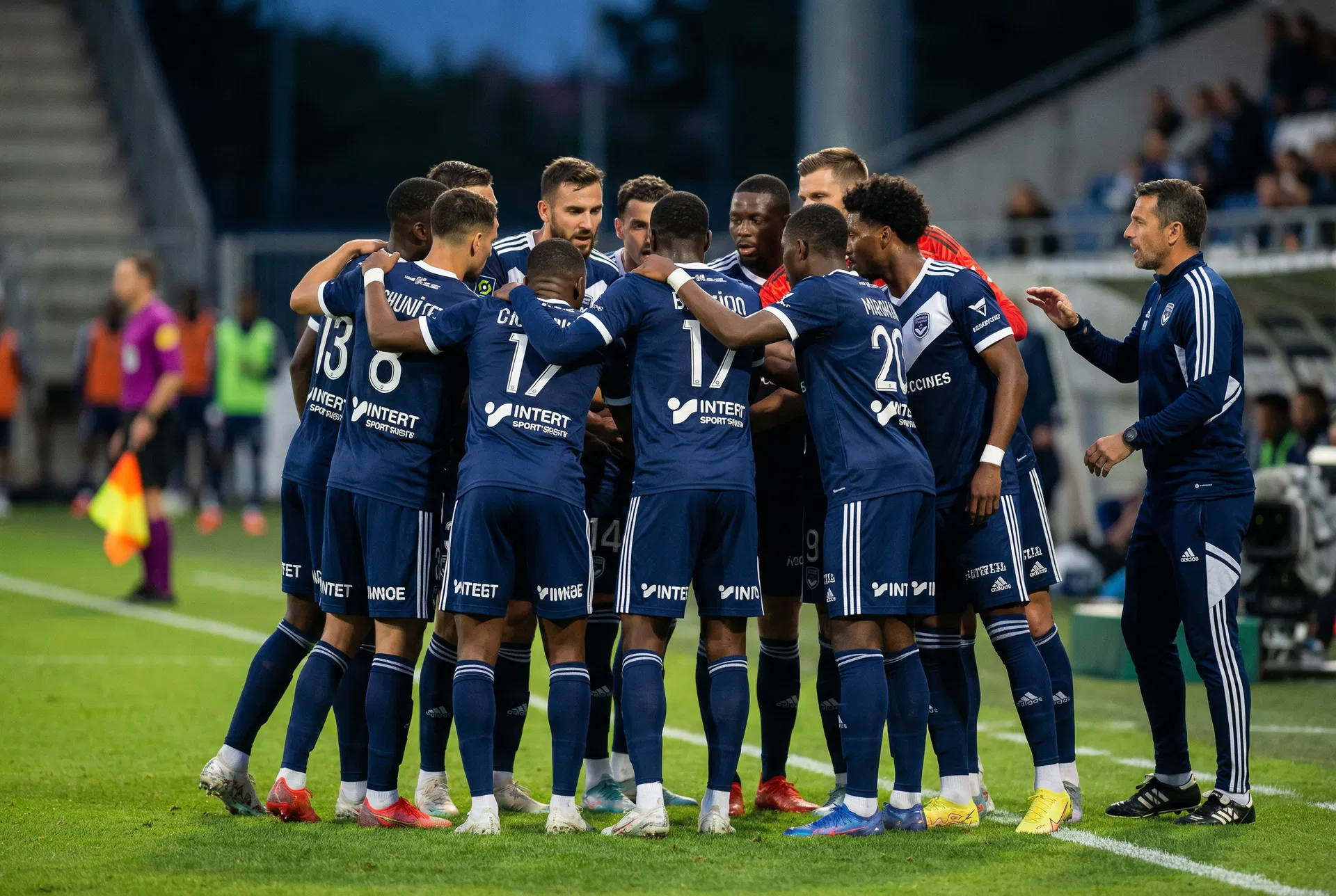 Soccer team in a huddle with coach, demonstrating team goal setting