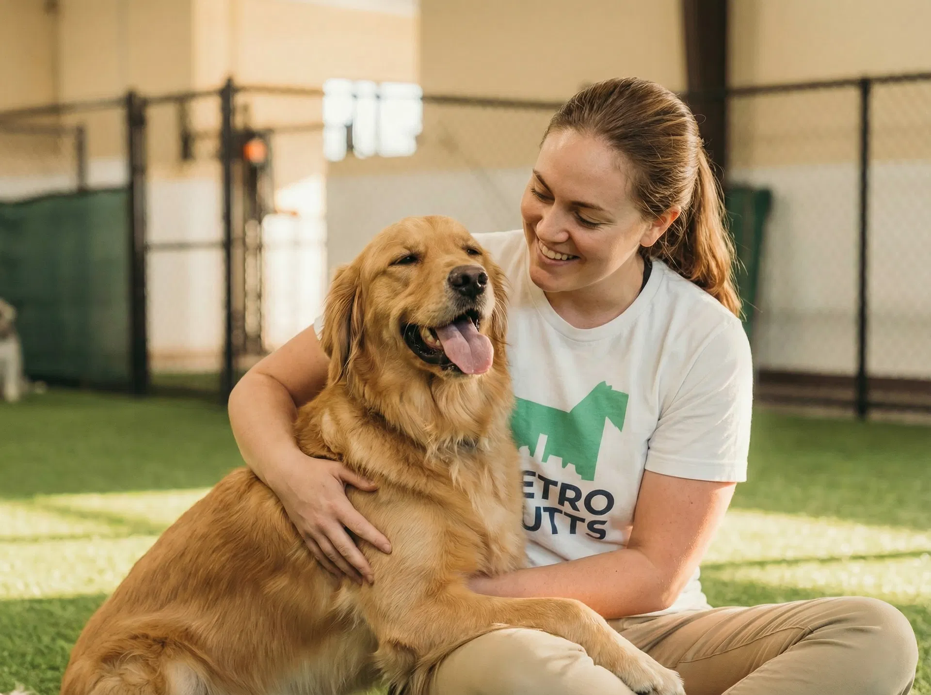 Metro Mutts staff member cuddling a golden retriever