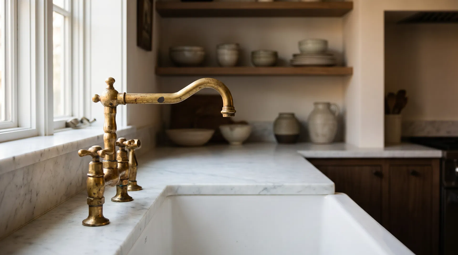 Luxury unlacquered brass bridge faucet on marble countertop