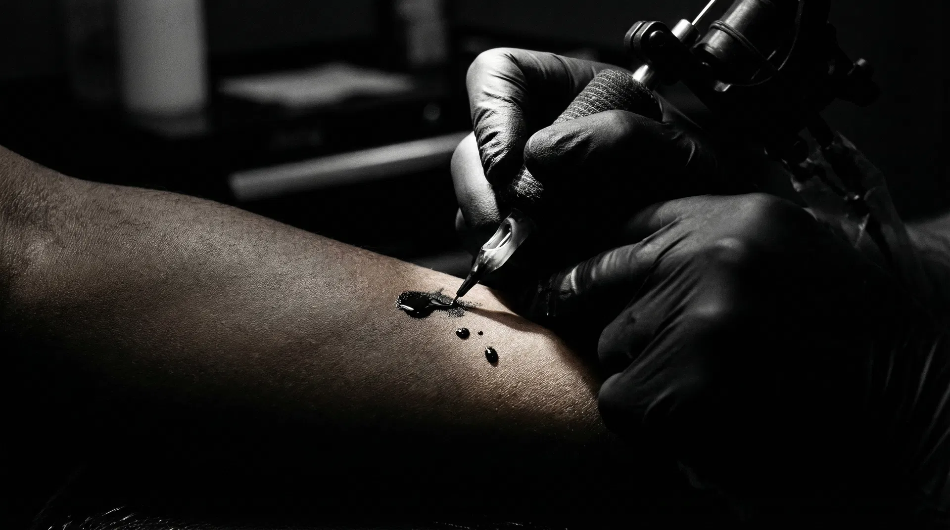 Tattoo artist at work — hands, needle, ink on skin