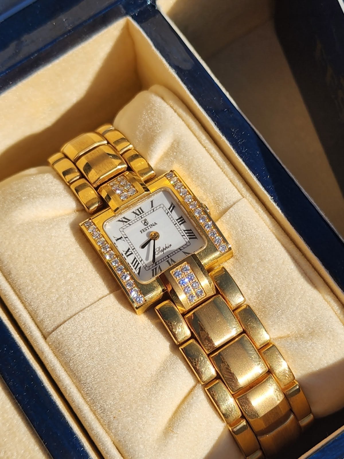 Festina gold-tone wrist watch — rectangular case, diamond-set bezel, diamond-accented bracelet links, white dial, Roman numeral hour markers, two-hand movement