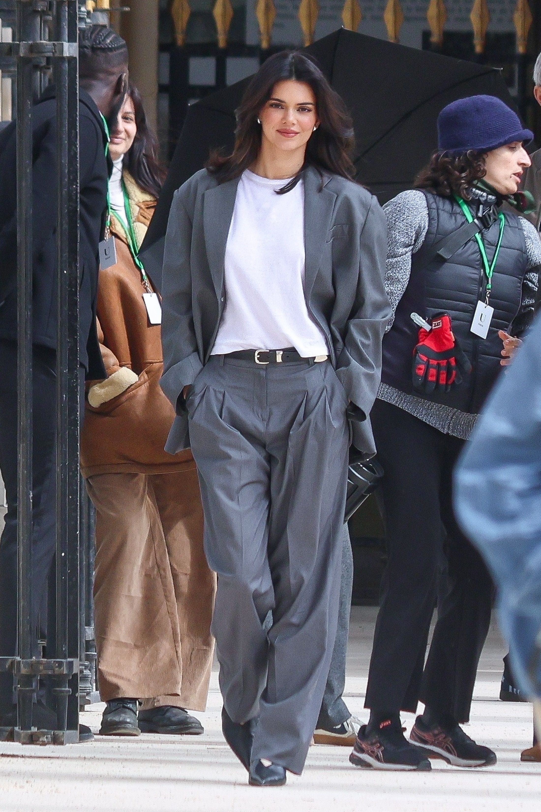 Kendall Jenner charcoal grey suit set — single-breasted blazer, wide lapels, pleated wide-leg trousers, black belt with silver buckle