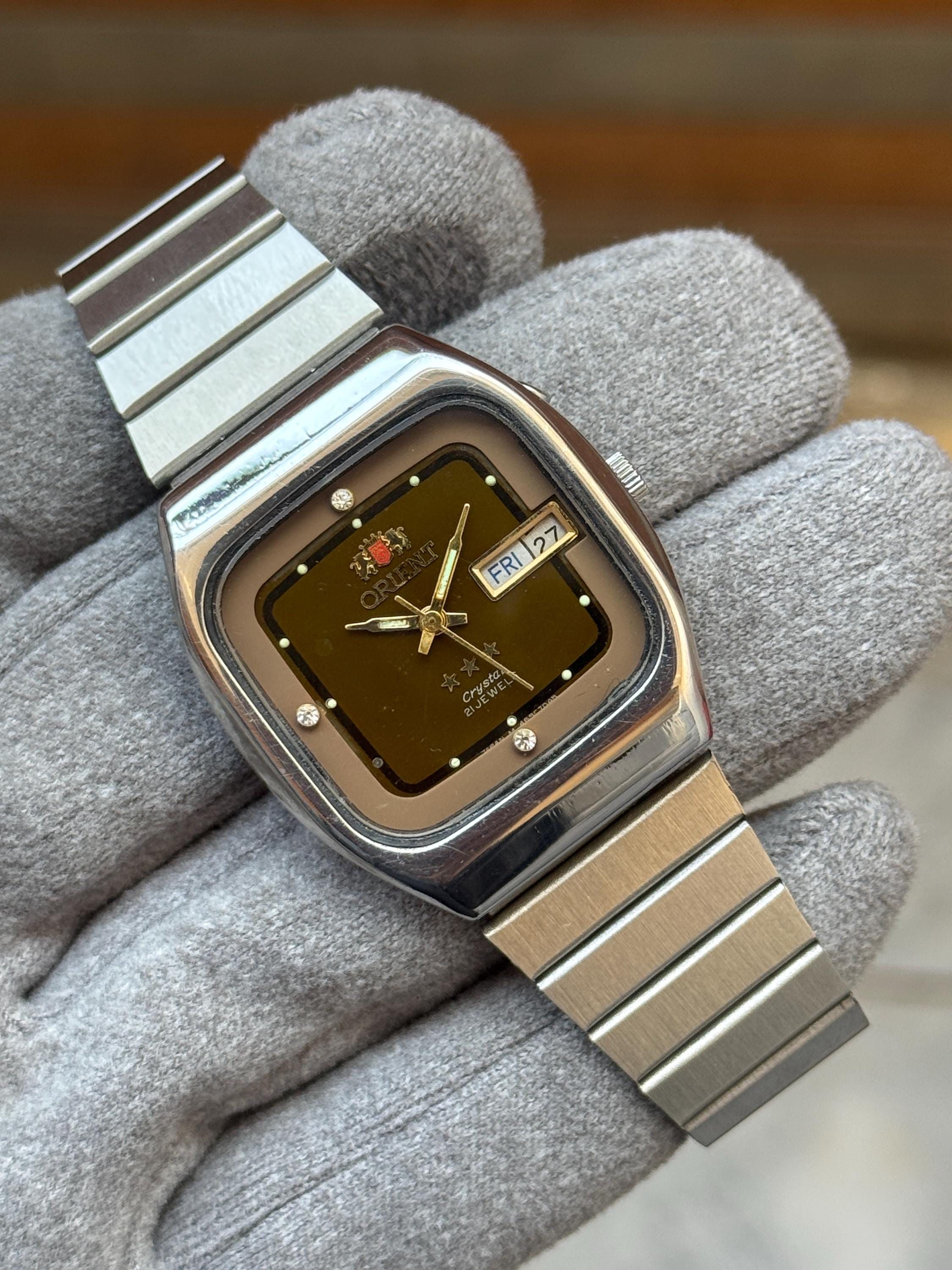 Orient silver and bronze wristwatch — tonneau case, integrated bracelet, day-date complication, applied hour markers with crystal accents, gold-tone hands