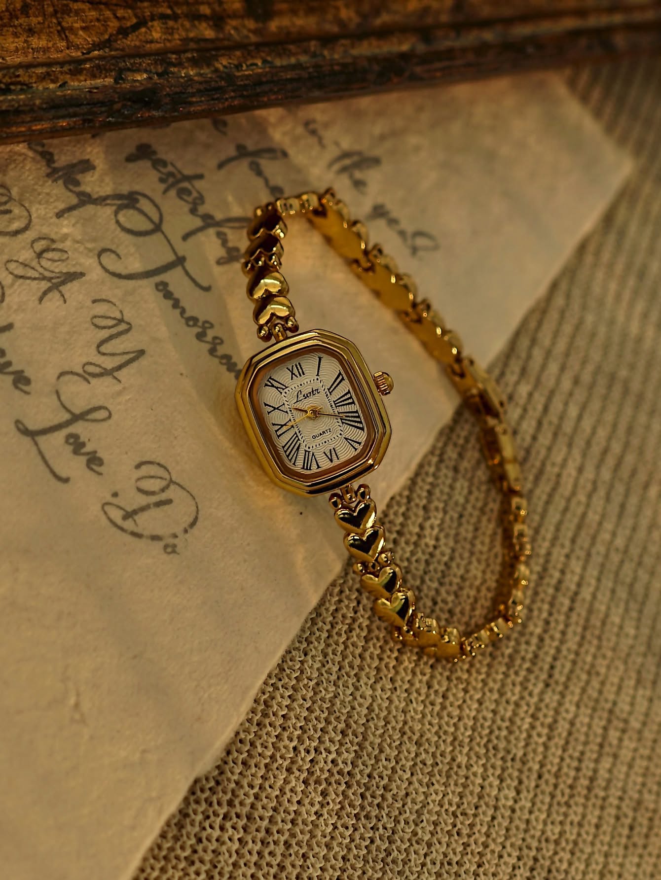 elegant gold wrist watch — octagonal gold case, white dial, Roman numerals, heart-shaped link bracelet