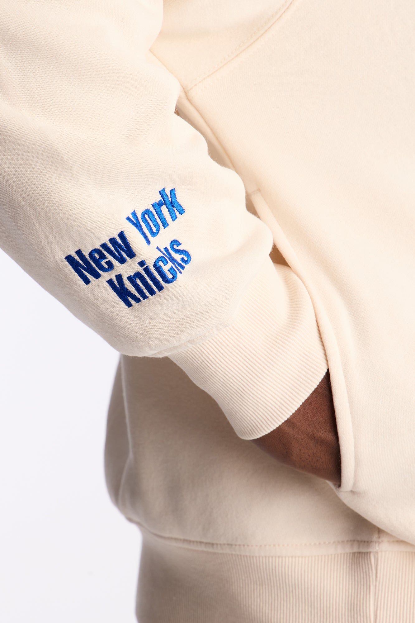 Sporty cream hoodie — ribbed cuffs, ribbed hem, embroidered 'New York Knicks' text on sleeve, front pouch pocket