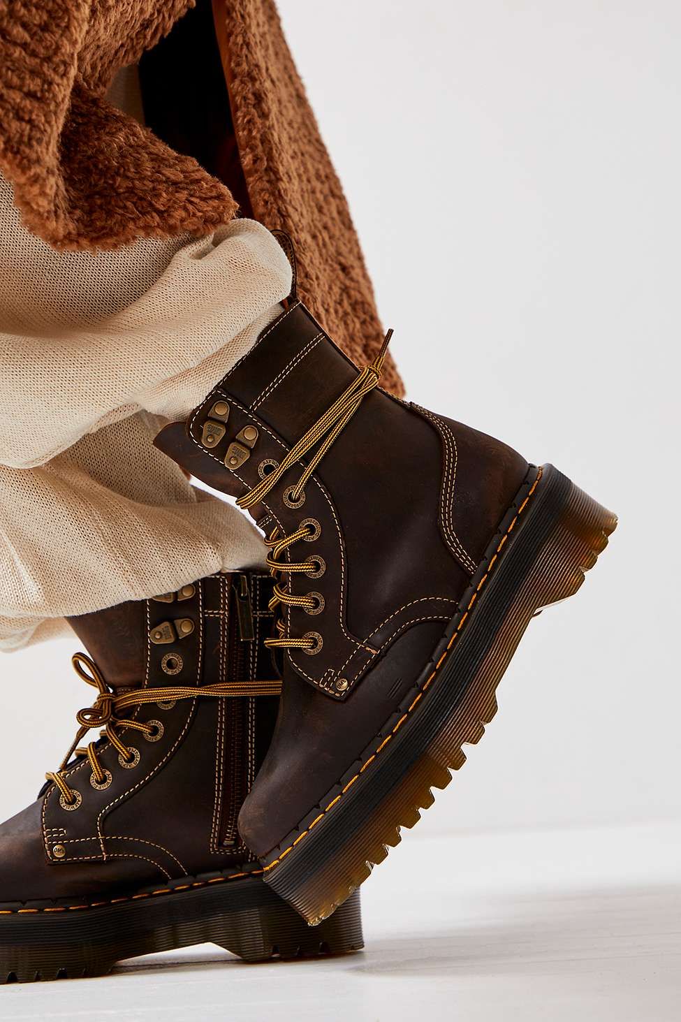 Dr. Martens dark brown distressed combat boots — platform sole, yellow stitching, lace-up front with metal eyelets and D-rings, side zipper, padded collar