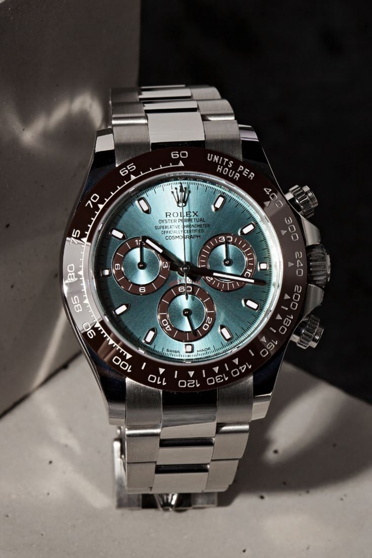 Rolex light blue dial, brown bezel, silver band chronograph watch — tachymeter bezel, three sub-dials, luminous hour markers, screw-down pushers, Oyster bracelet