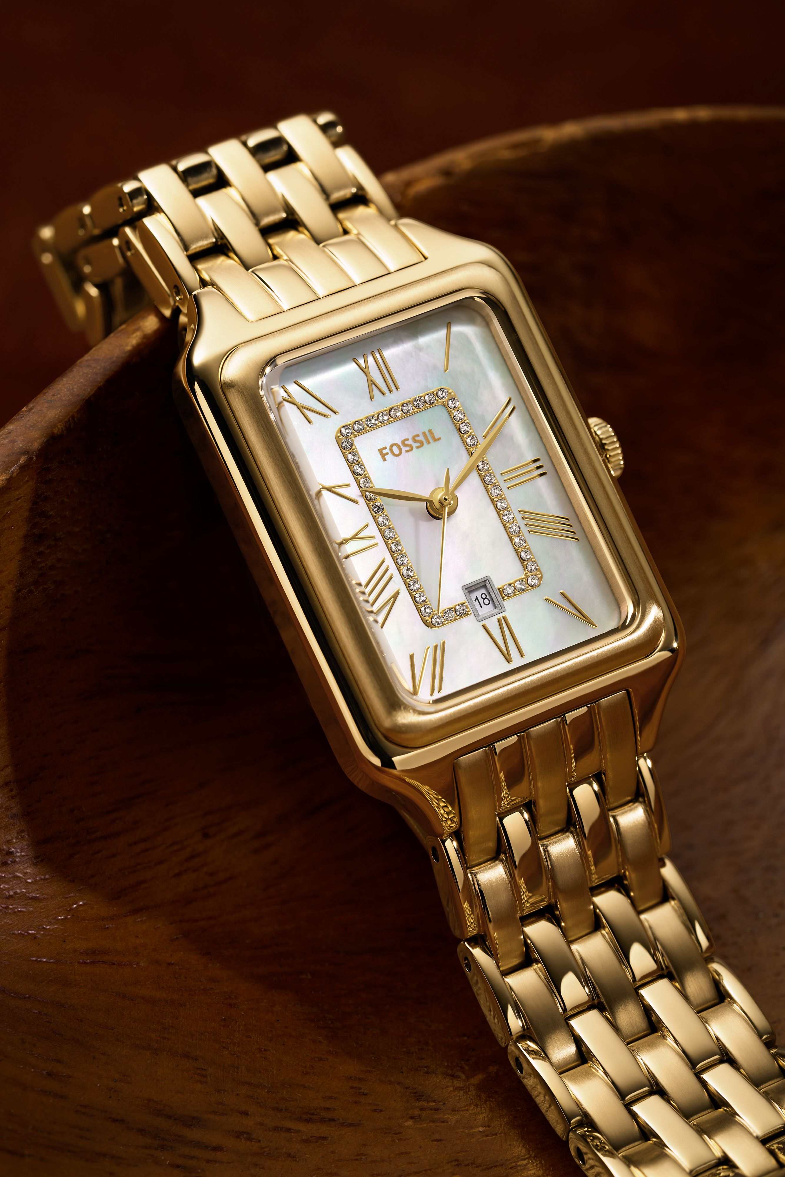 Fossil gold wristwatch — rectangular case, mother-of-pearl dial, Roman numeral hour markers, crystal-set inner bezel, date window, link bracelet