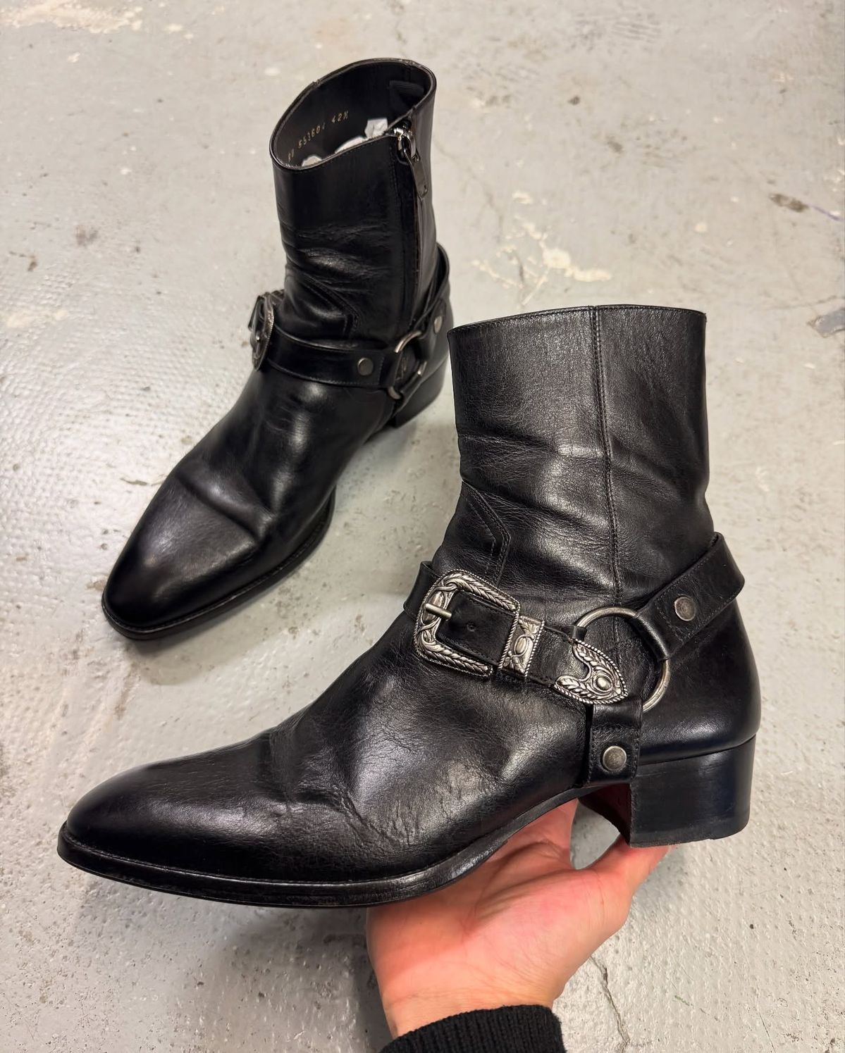 rocker black ankle boots — pointed toe, Cuban heel, side zipper, decorative harness strap with ornate silver buckles and O-ring