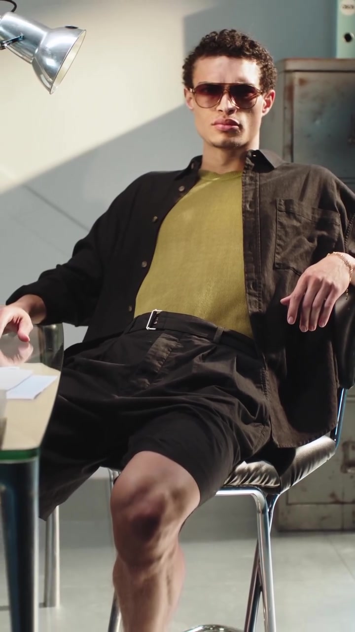 casual black and olive green men's outfit — button-down shirt, chest pockets, pleated shorts, belted waist