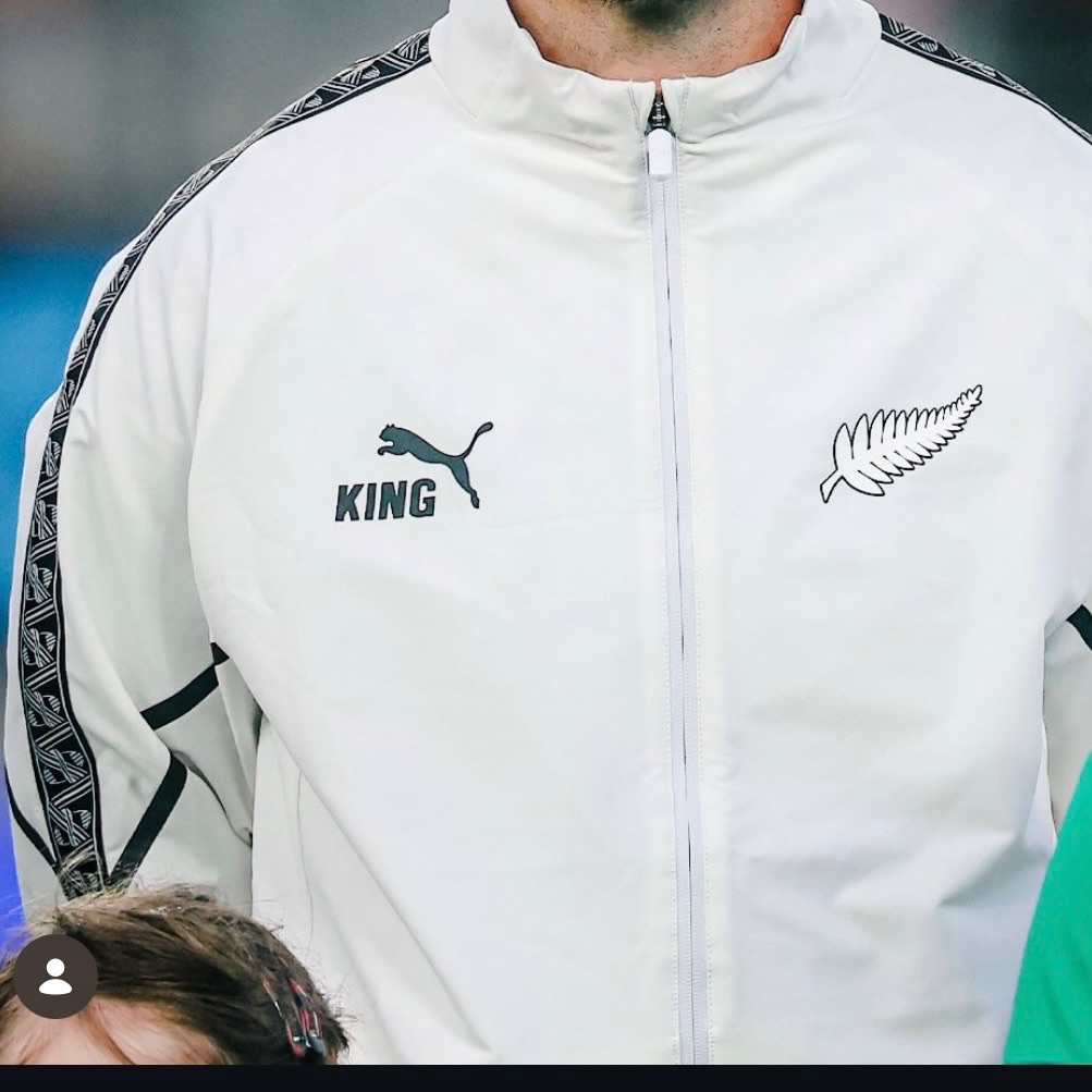 Puma Puma track jacket full zip front, stand-up collar, raglan sleeves, black and white patterned tape stripes on shoulders and sleeves, Puma King logo on left chest, New Zealand Silver Fern logo on right chest cream white solid with patterned side stripes sportswear
