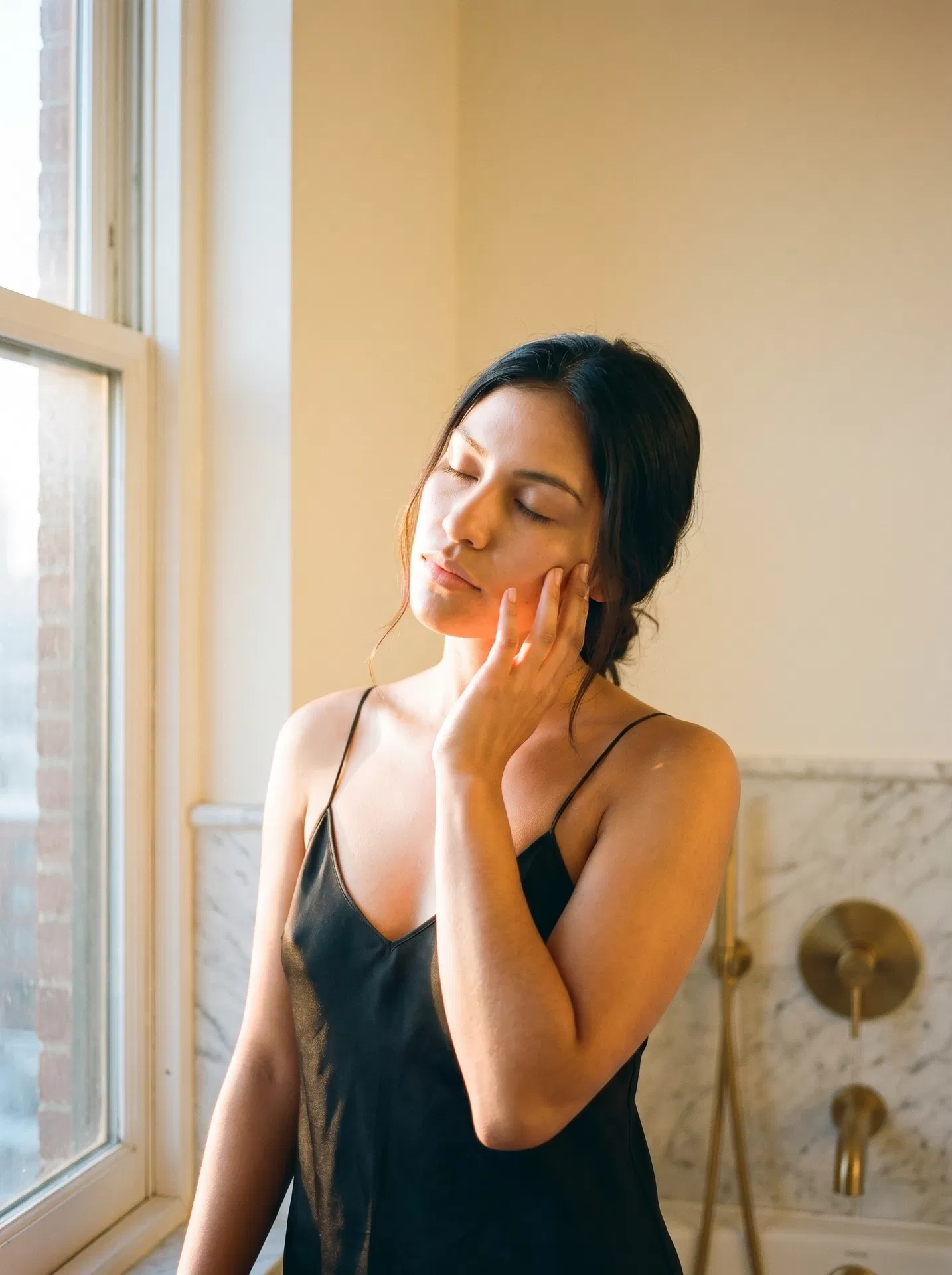 Woman applying OH FACE cream in morning light