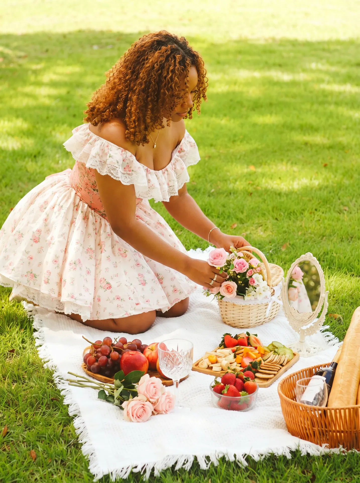 Woman in floral dress arranging flowers on a picnic blanket