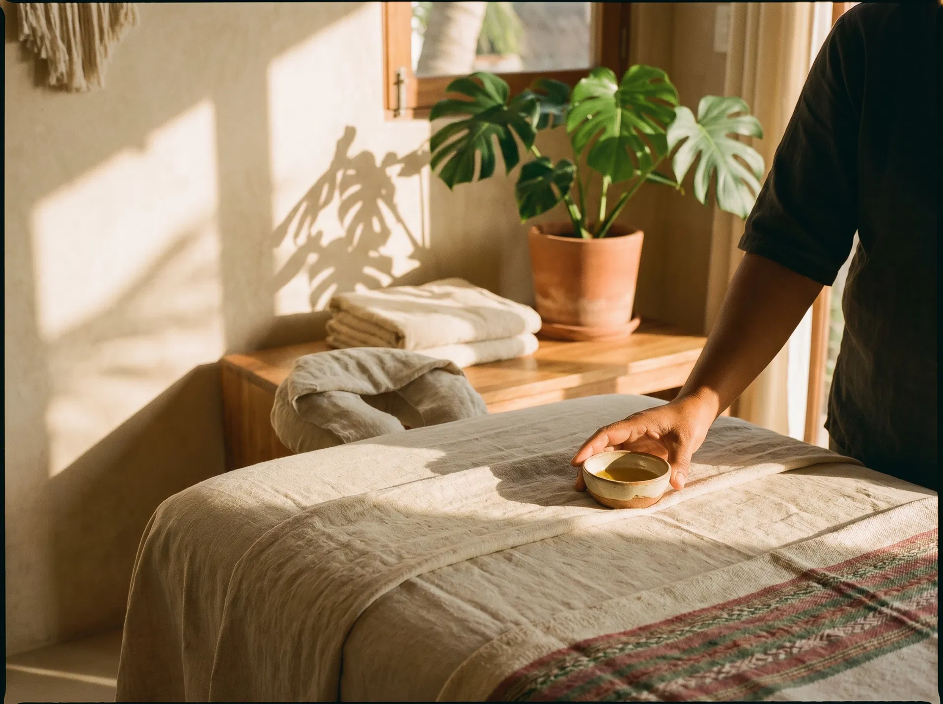 in-home massage Oaxaca setup with folded linens, warm wood, and local therapist hand detail