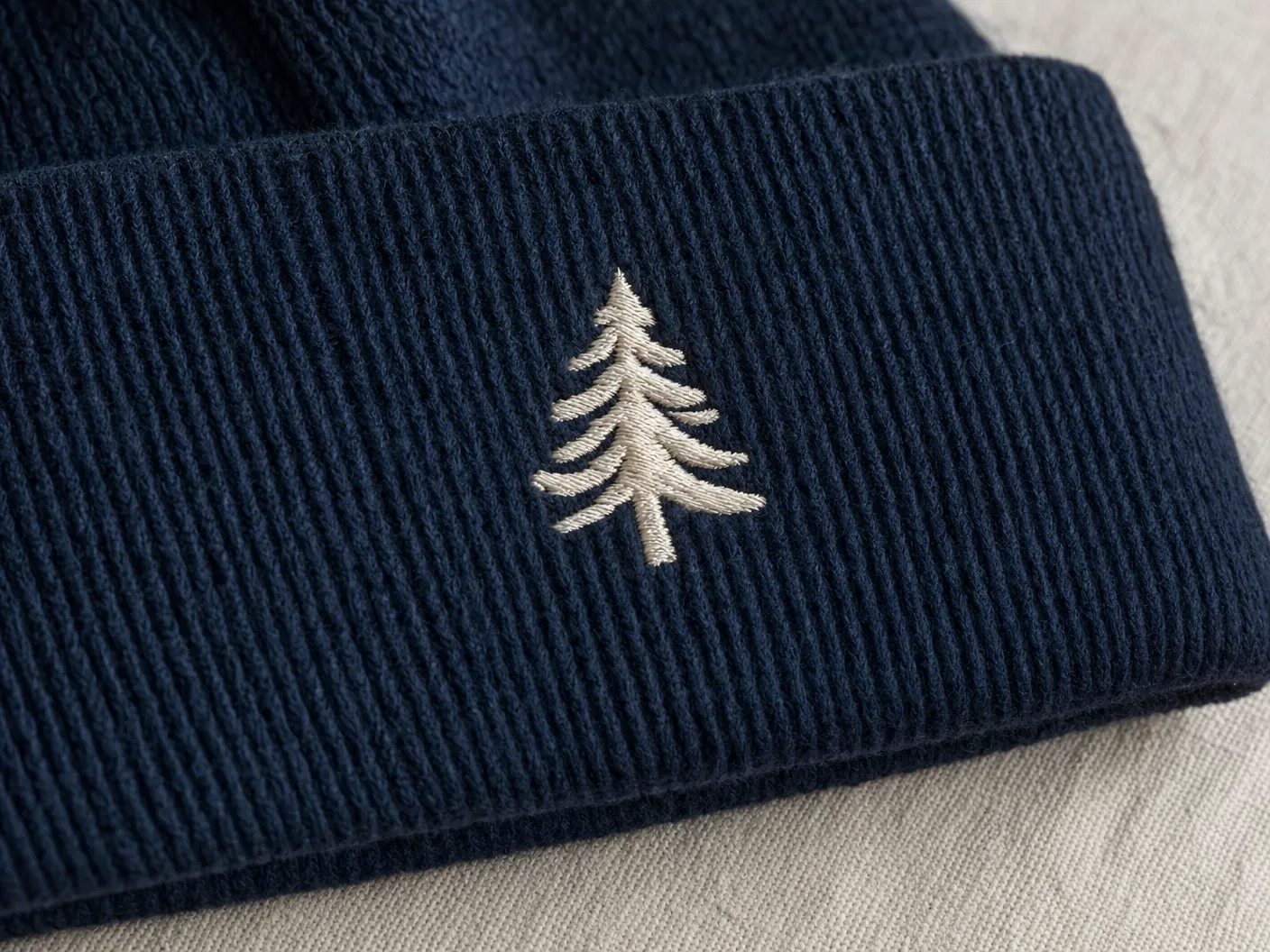 Flat embroidery pine tree logo on navy beanie cuff
