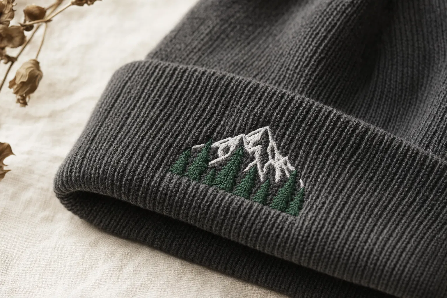 Charcoal beanie with embroidered mountain and tree logo on ribbed cuff