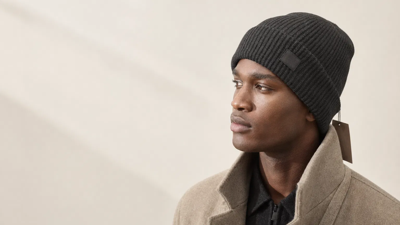 Premium fashion model wearing a charcoal custom rib knit beanie with subtle label detail