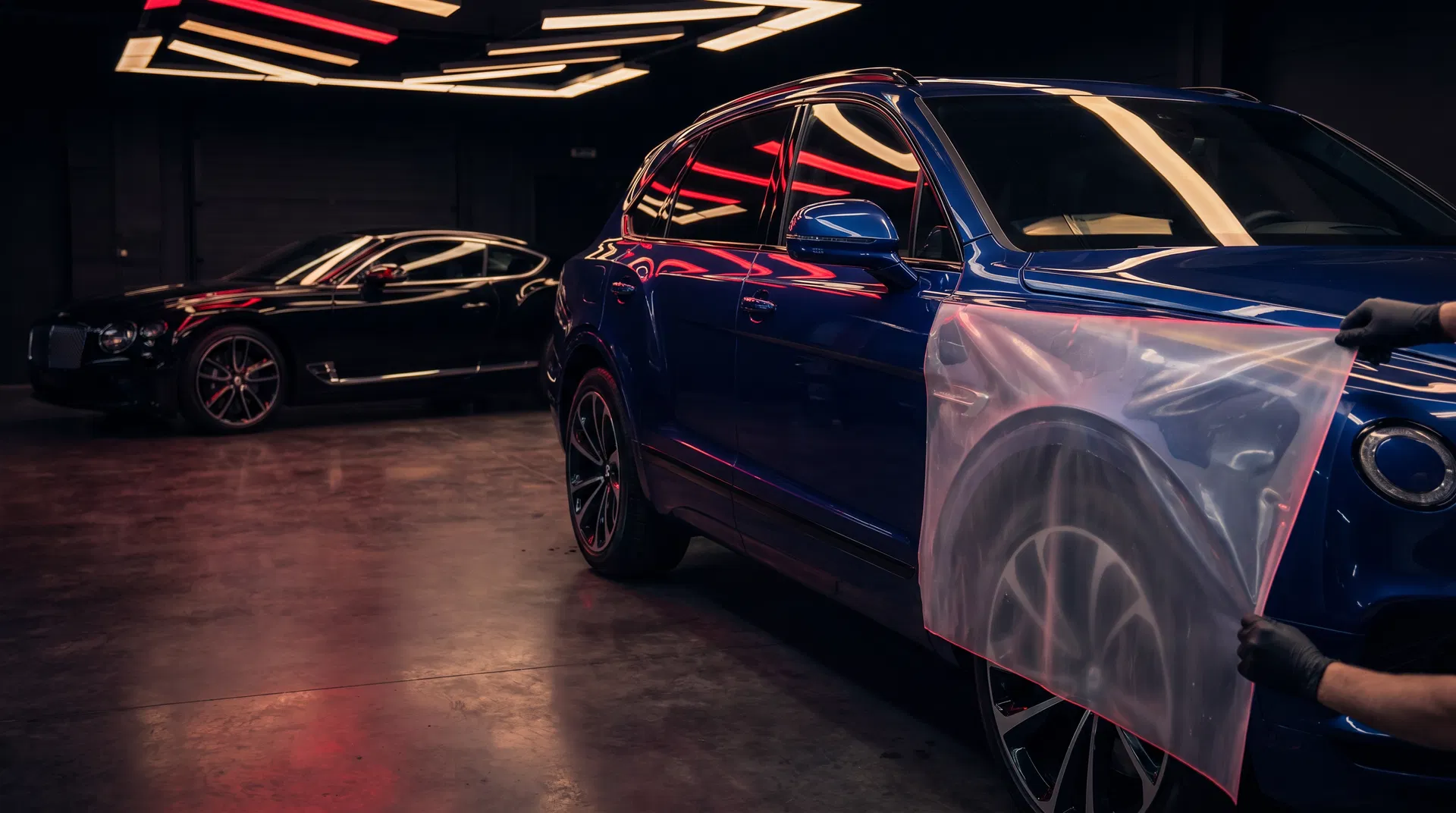 Luxury SUV receiving paint protection film with premium tint reflections