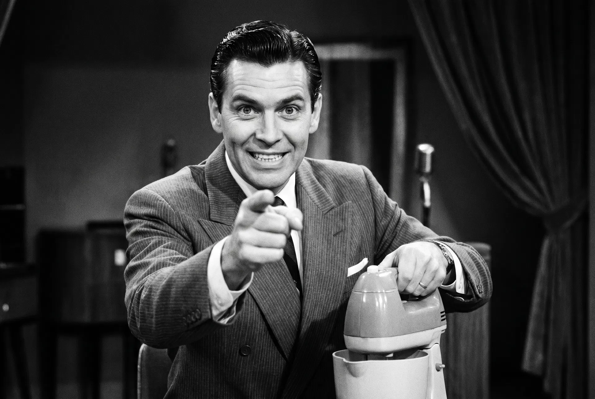 A retro TV salesman with an artificial smile pointing at the camera