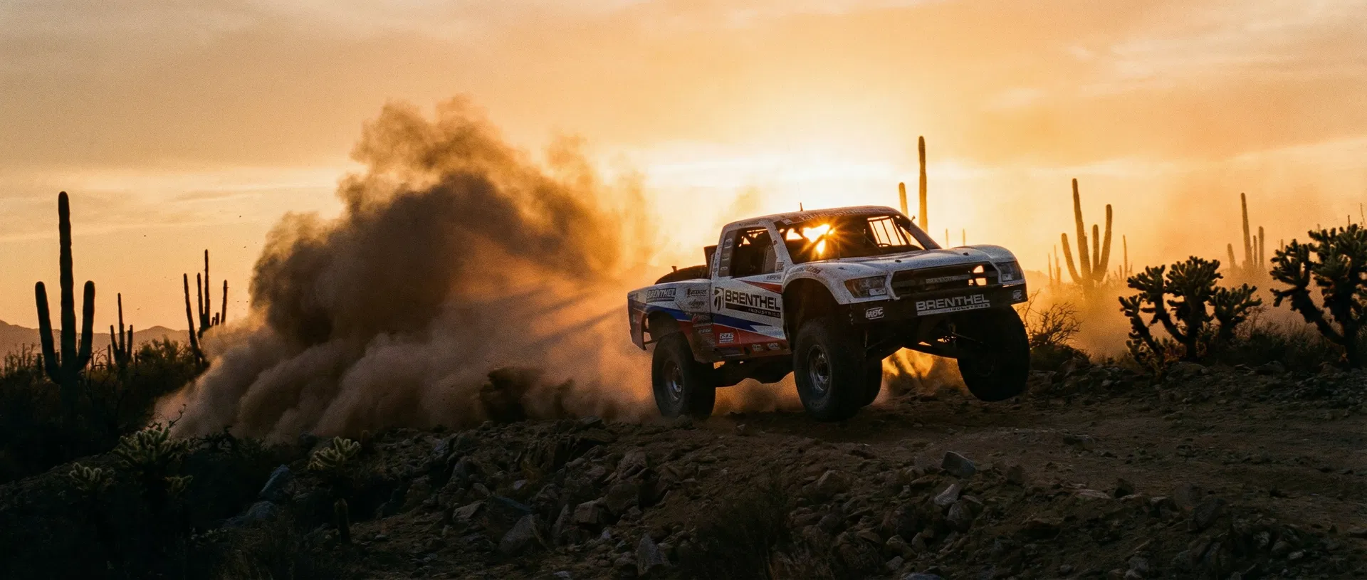 Trophy truck racing through Baja desert at sunset